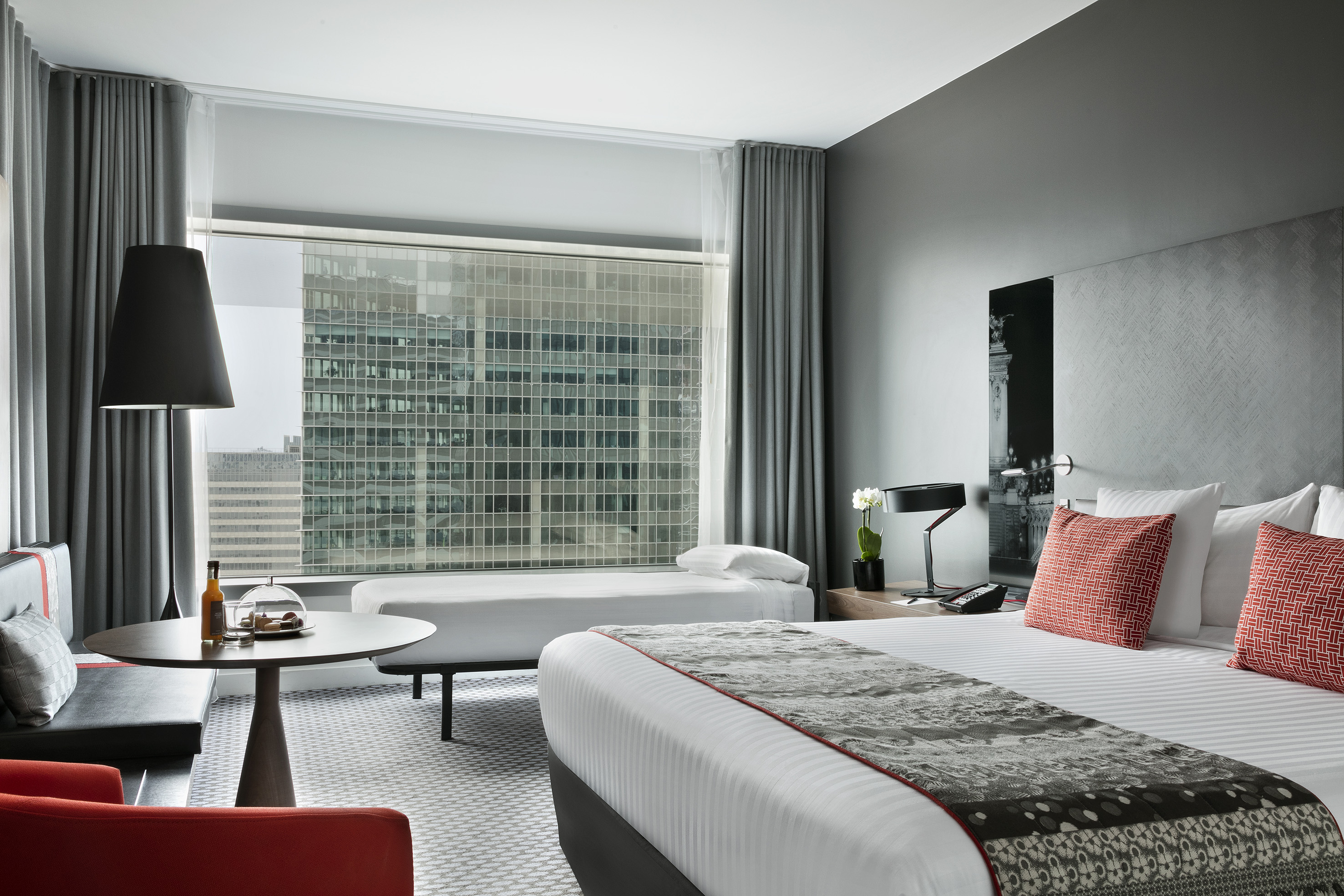 Modern hotel suite with city view, king bed, daybed, and stylish seating.