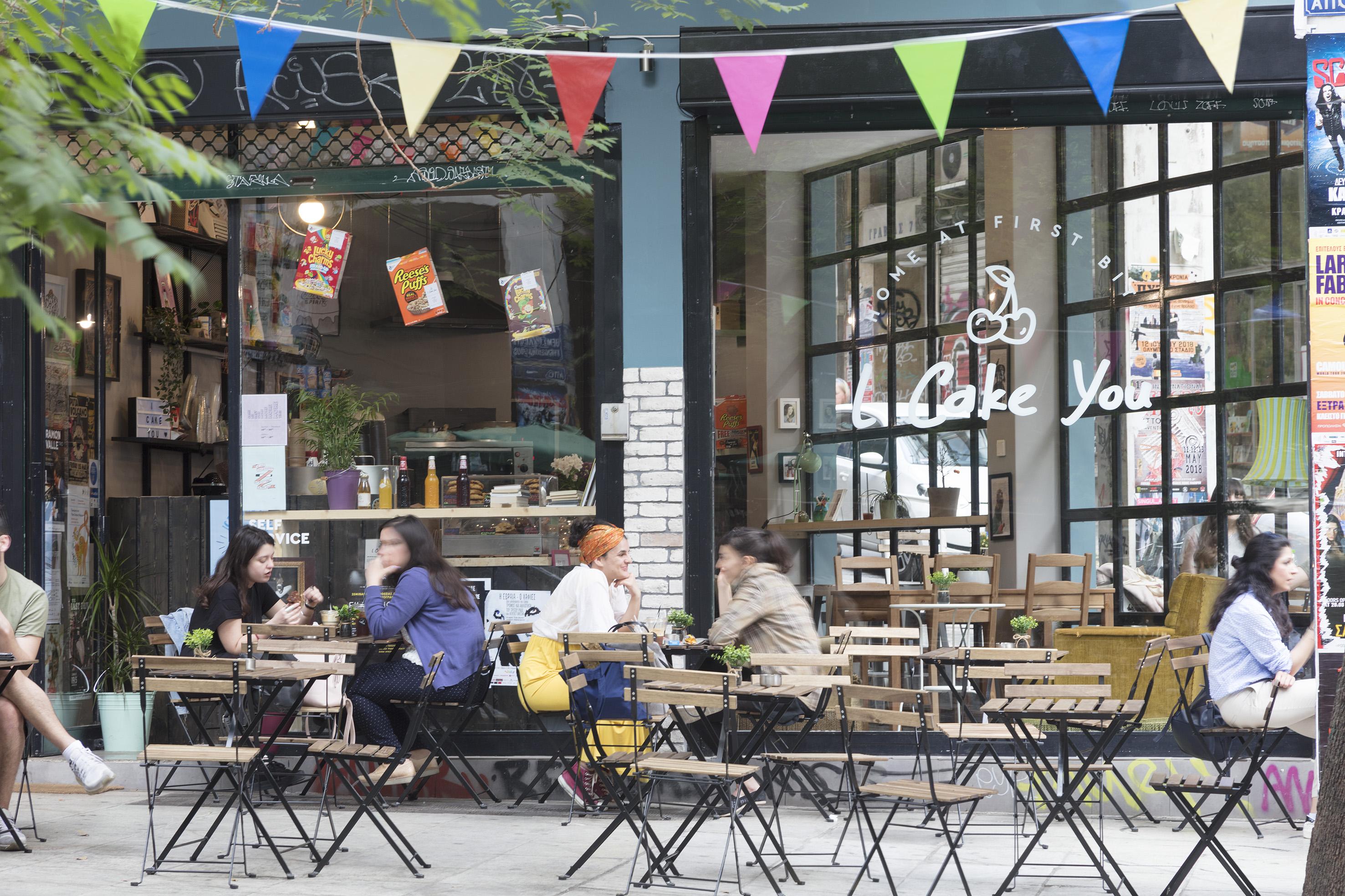 Customers at a vibrant street cafe with outdoor tables and colorful bunting.