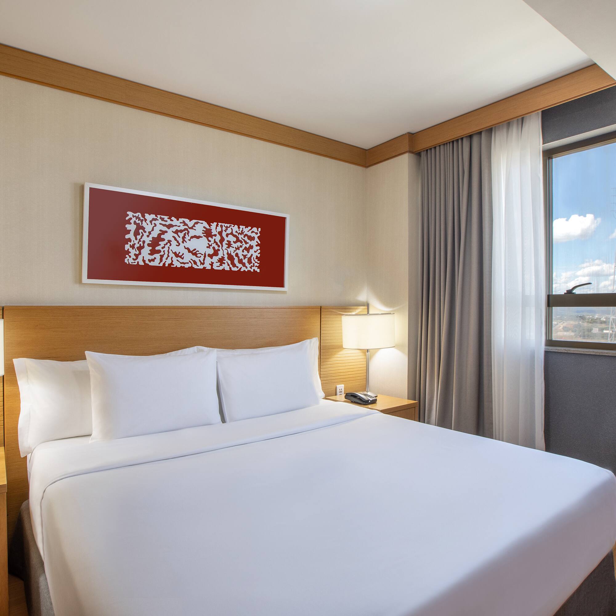 a bed with white sheets and a lamp on the side