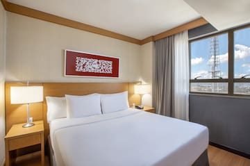 a bed with white sheets and a lamp on the side