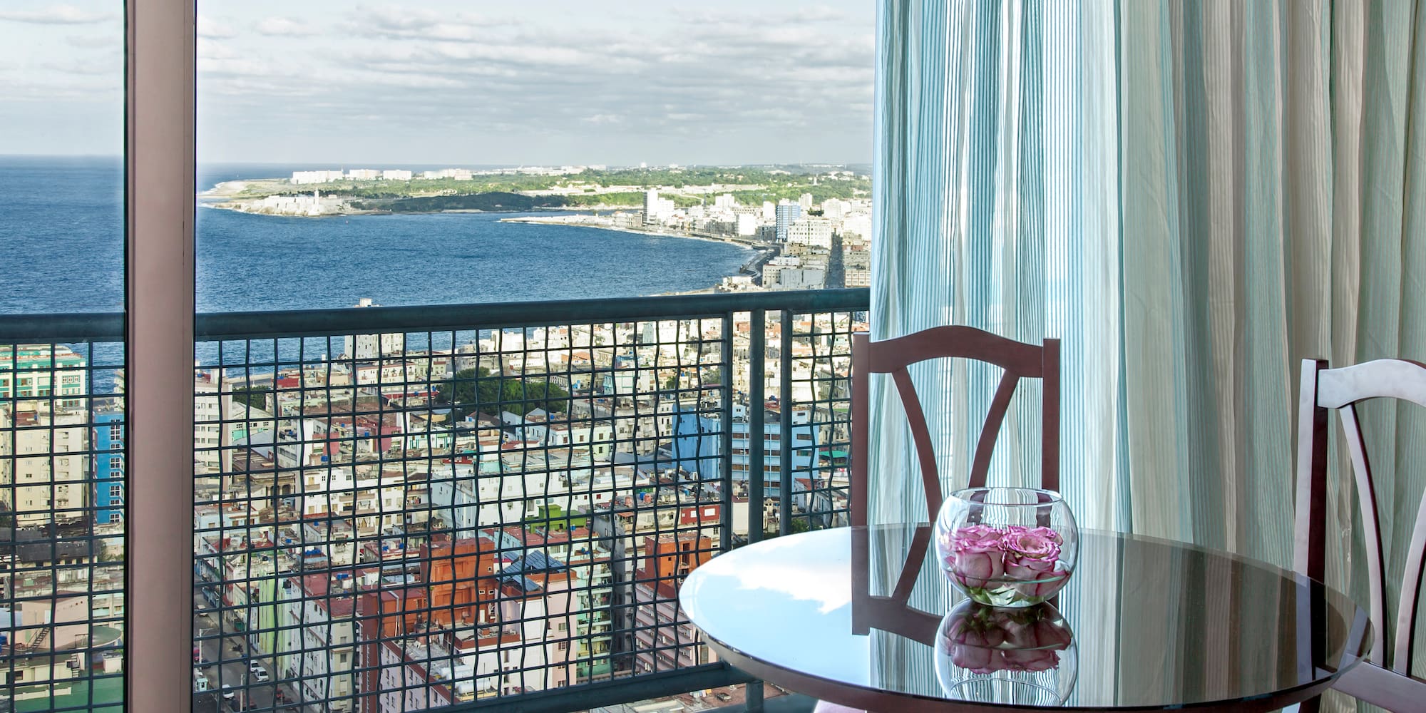 a table with a vase of flowers on it overlooking a city