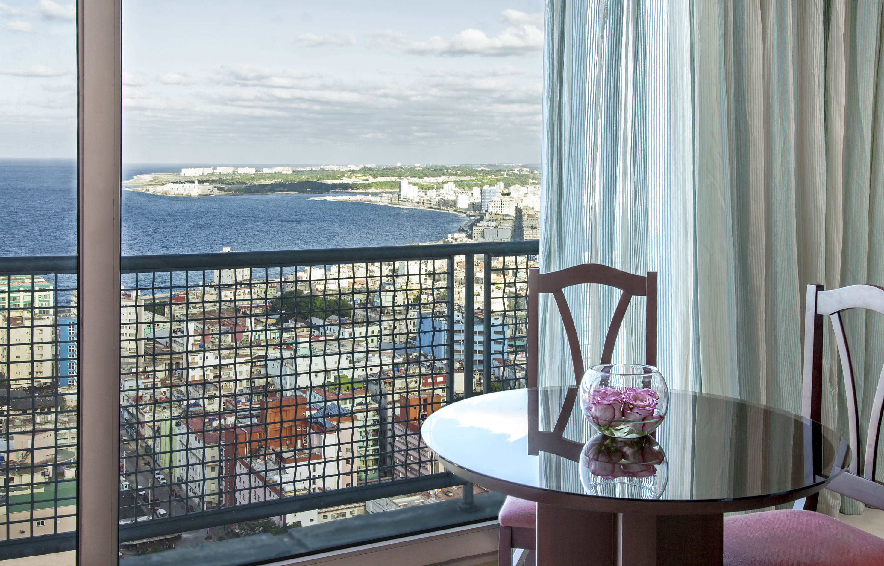 a table with a vase of flowers on it overlooking a city