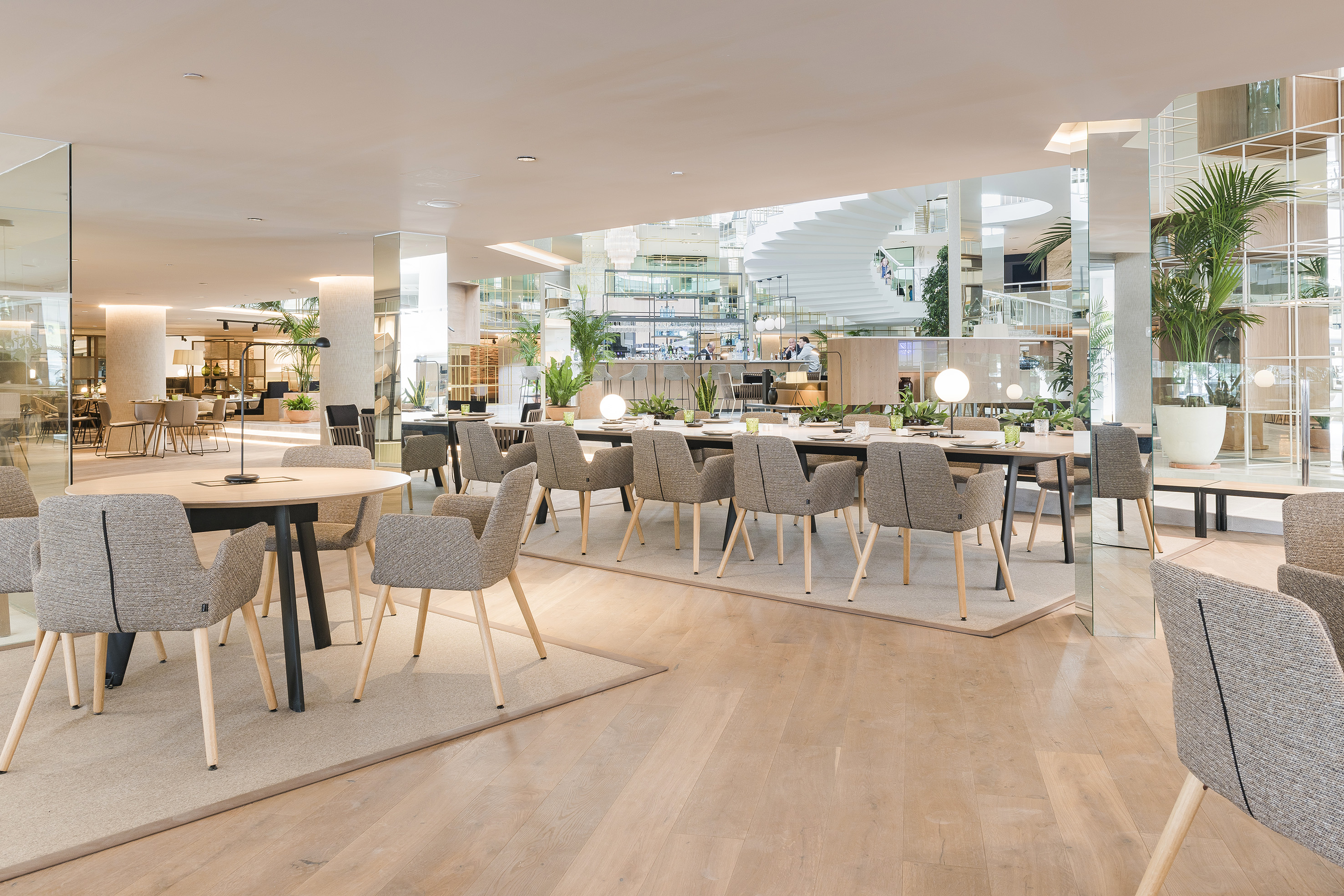 Modern hotel restaurant with grey chairs, long tables, and bright, open space.