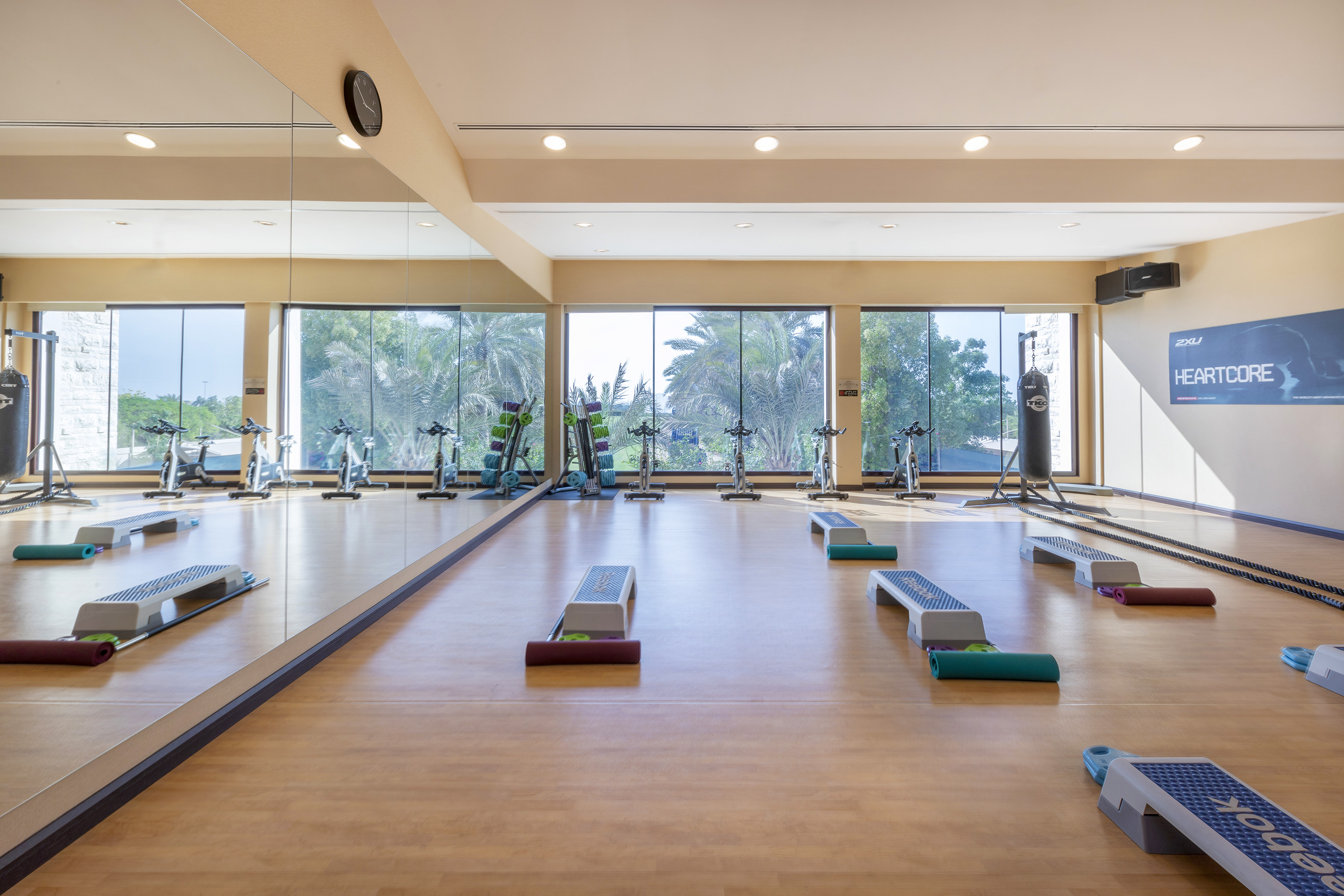 Fitness studio with spin bikes, aerobic steps, punching bag, mirrored walls.