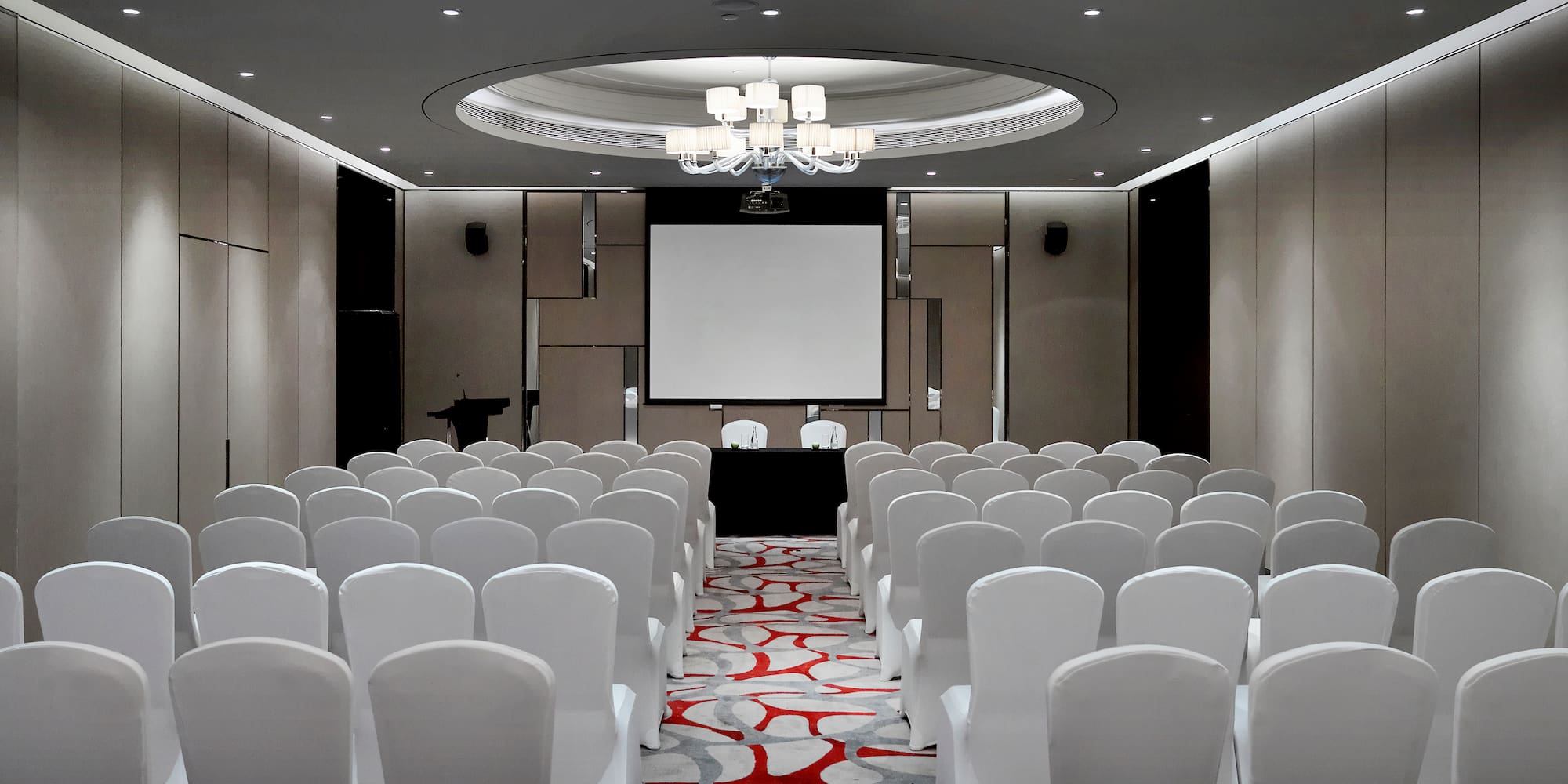 a room with white chairs and a projector screen