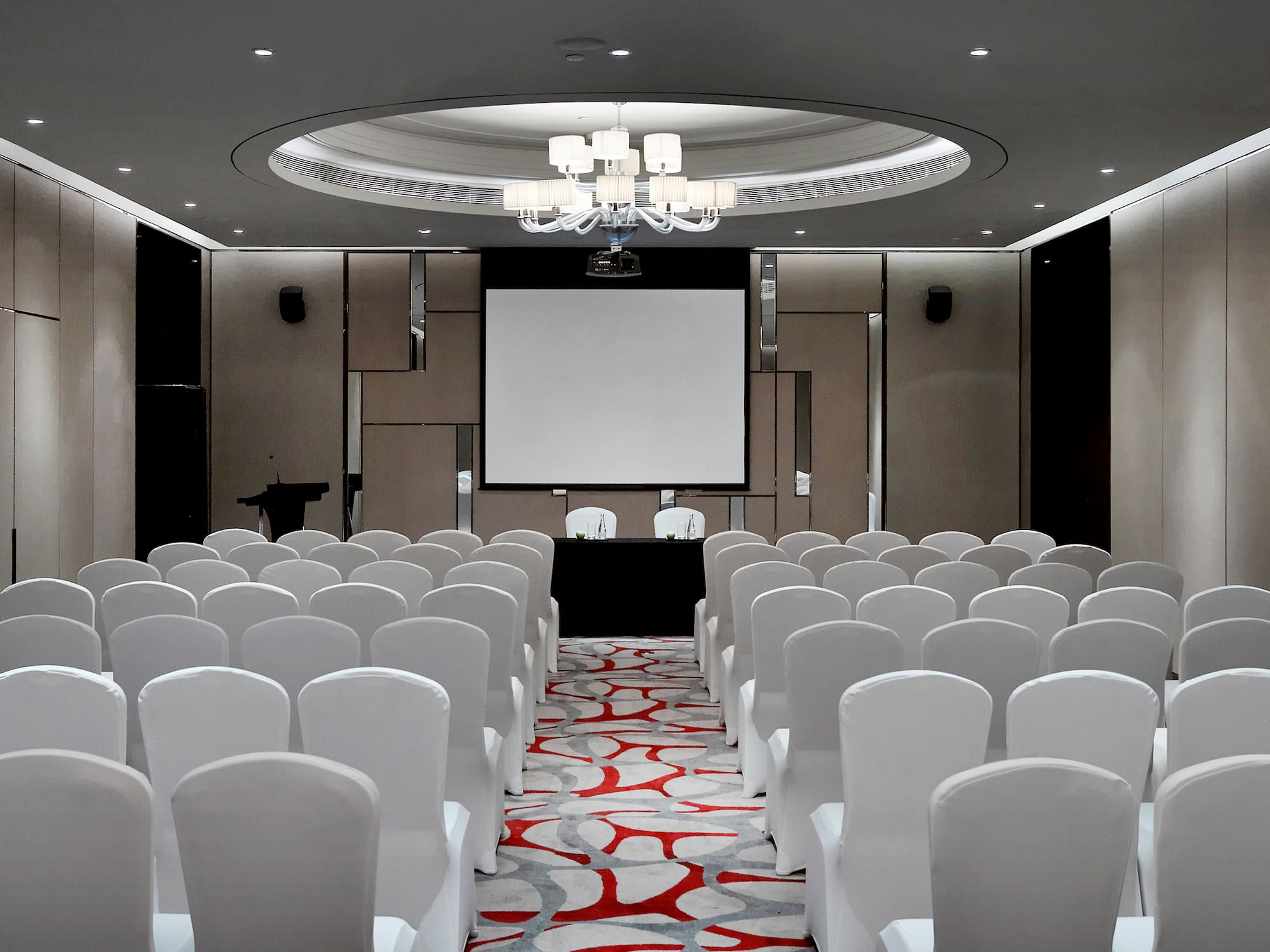 a room with white chairs and a projector screen