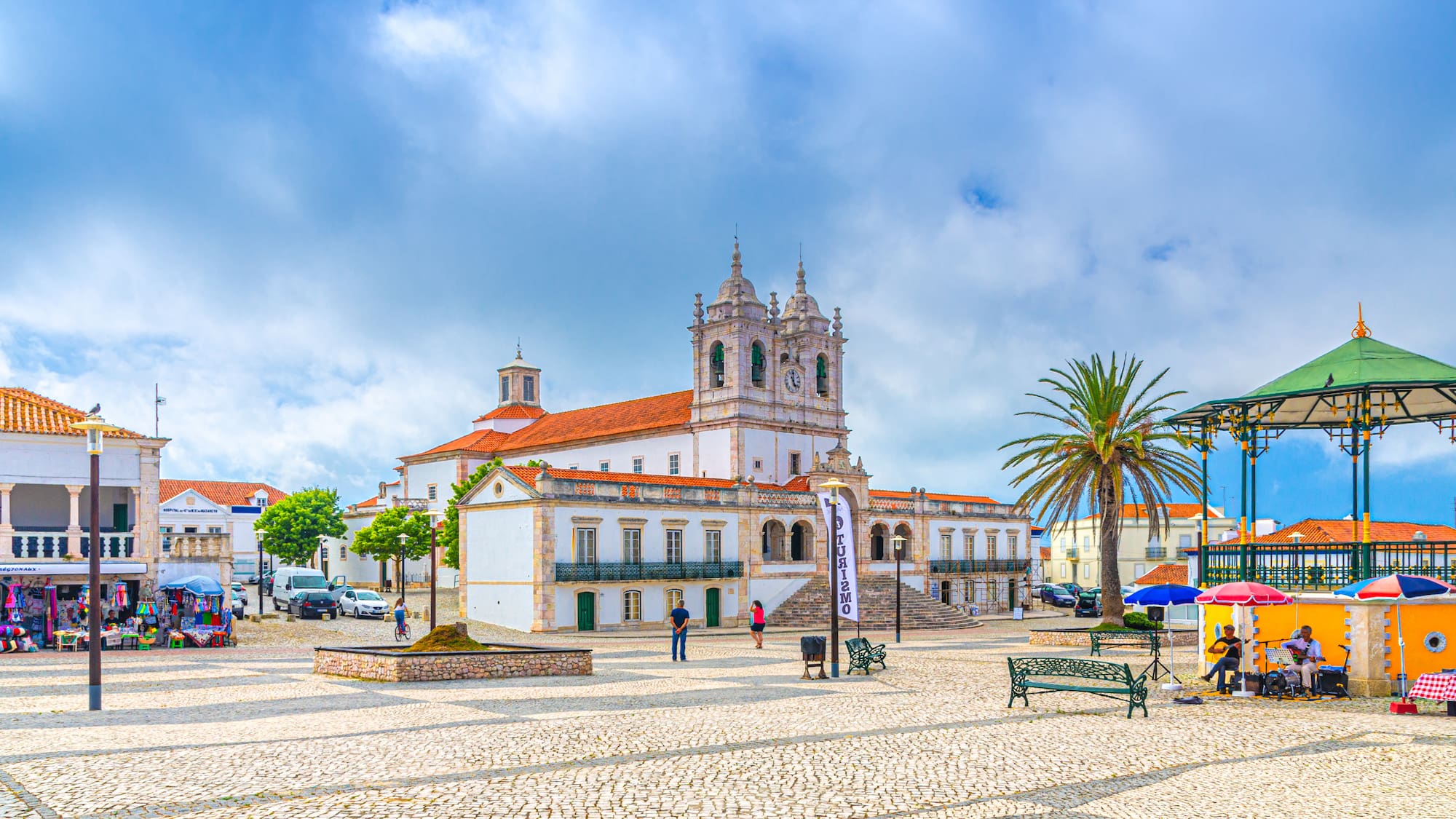 a building with a red roof and a white building with trees and a blue sky
