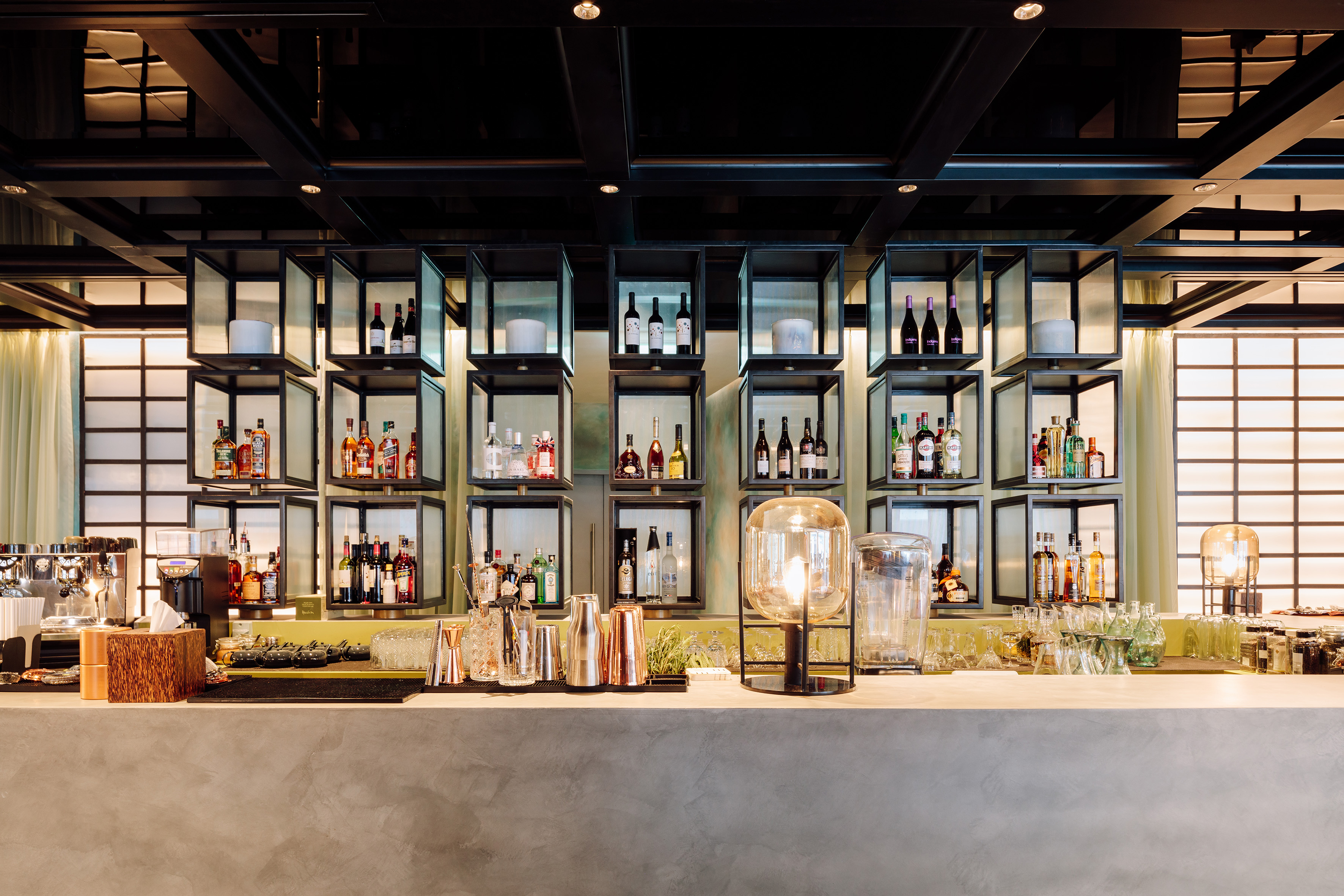 Contemporary bar design with concrete counter, backlit shelves of liquor bottles.