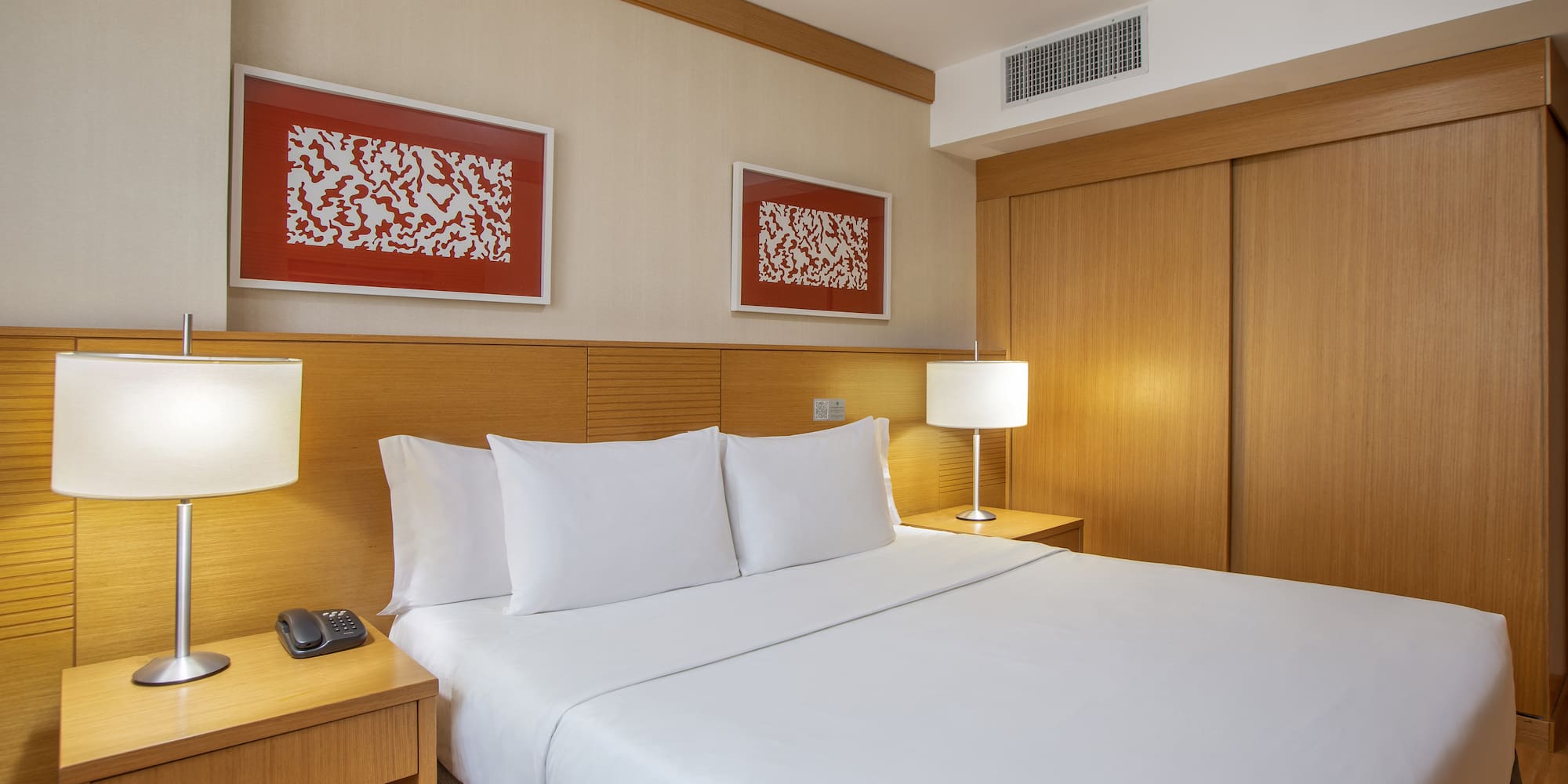 a bed with white sheets and a lamp next to a closet