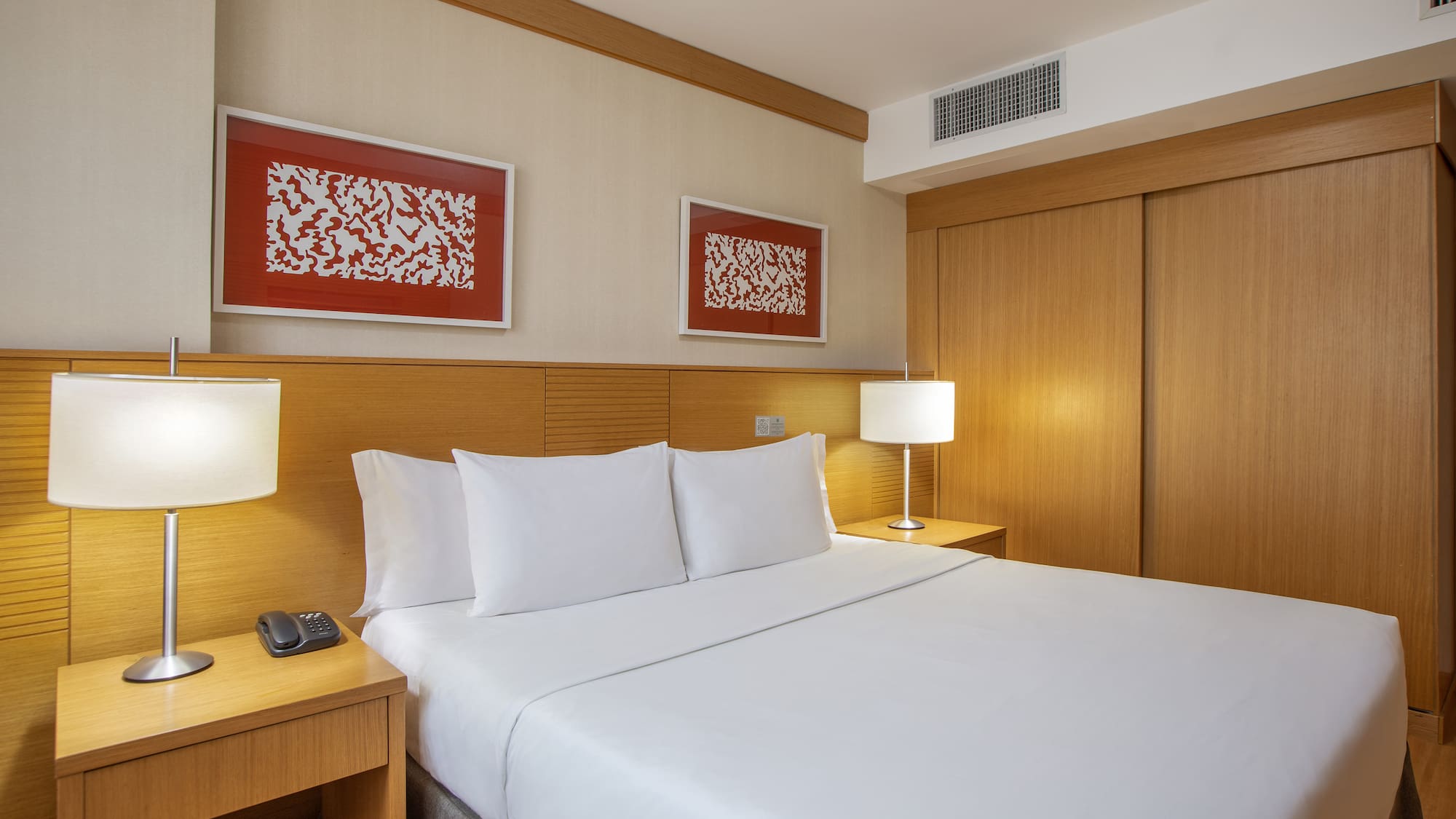 a bed with white sheets and a lamp next to a closet