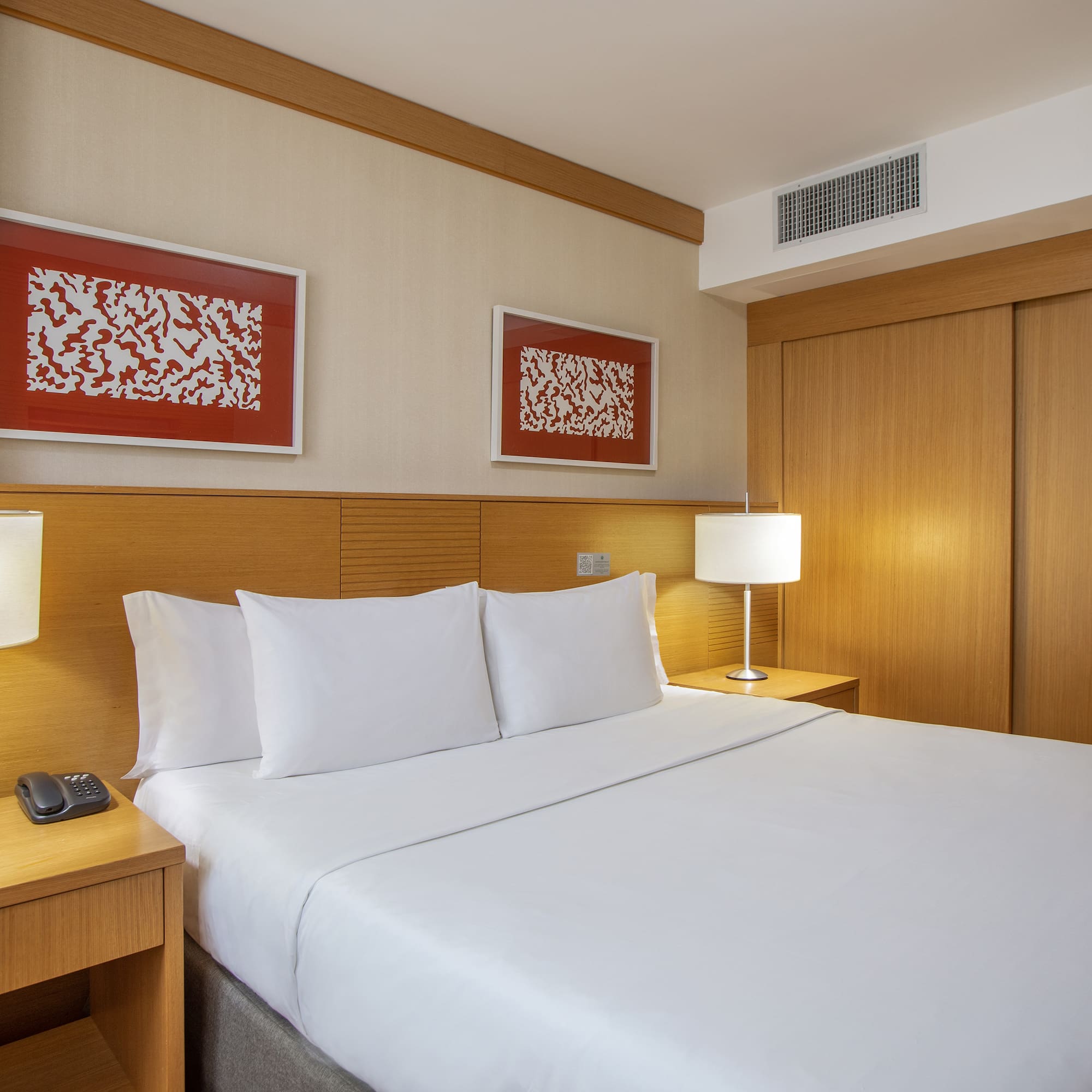 a bed with white sheets and a lamp next to a closet