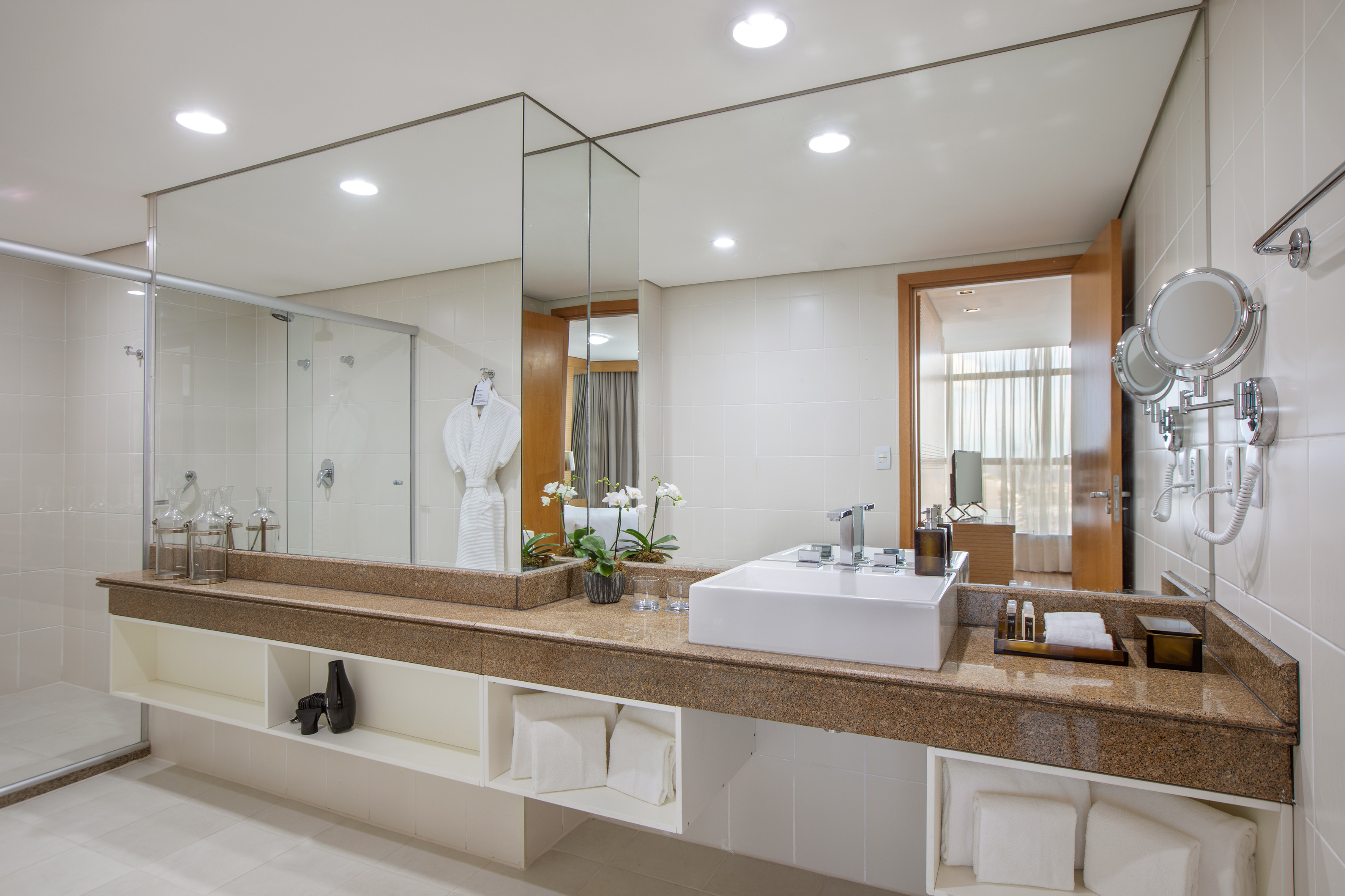Modern bathroom with granite vanity, white vessel sink, large mirror, and glass shower.