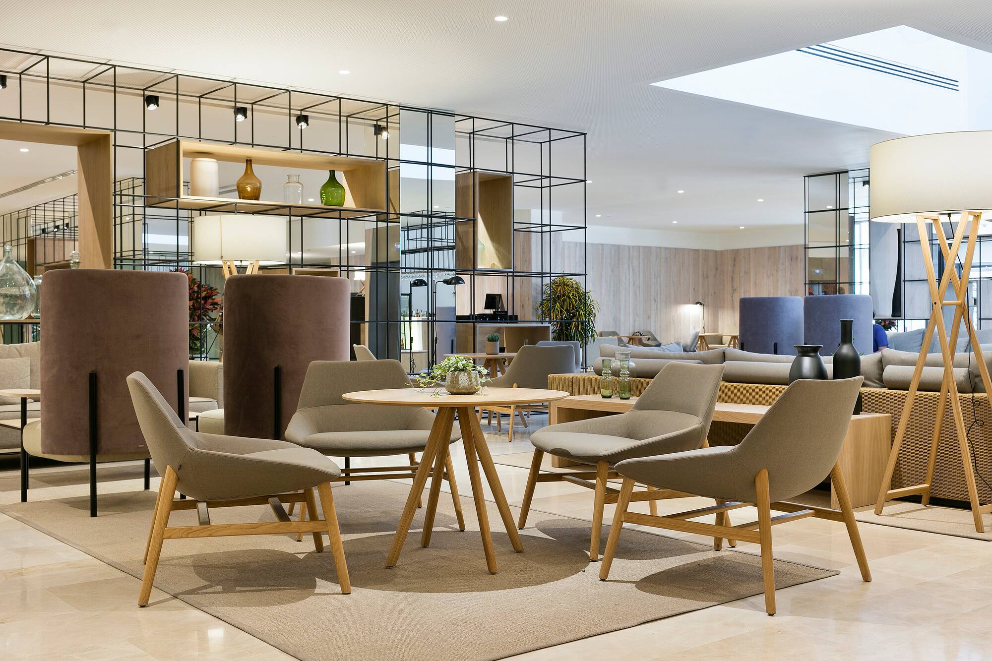 Chic modern lounge with comfortable seating, round table, and decorative divider.