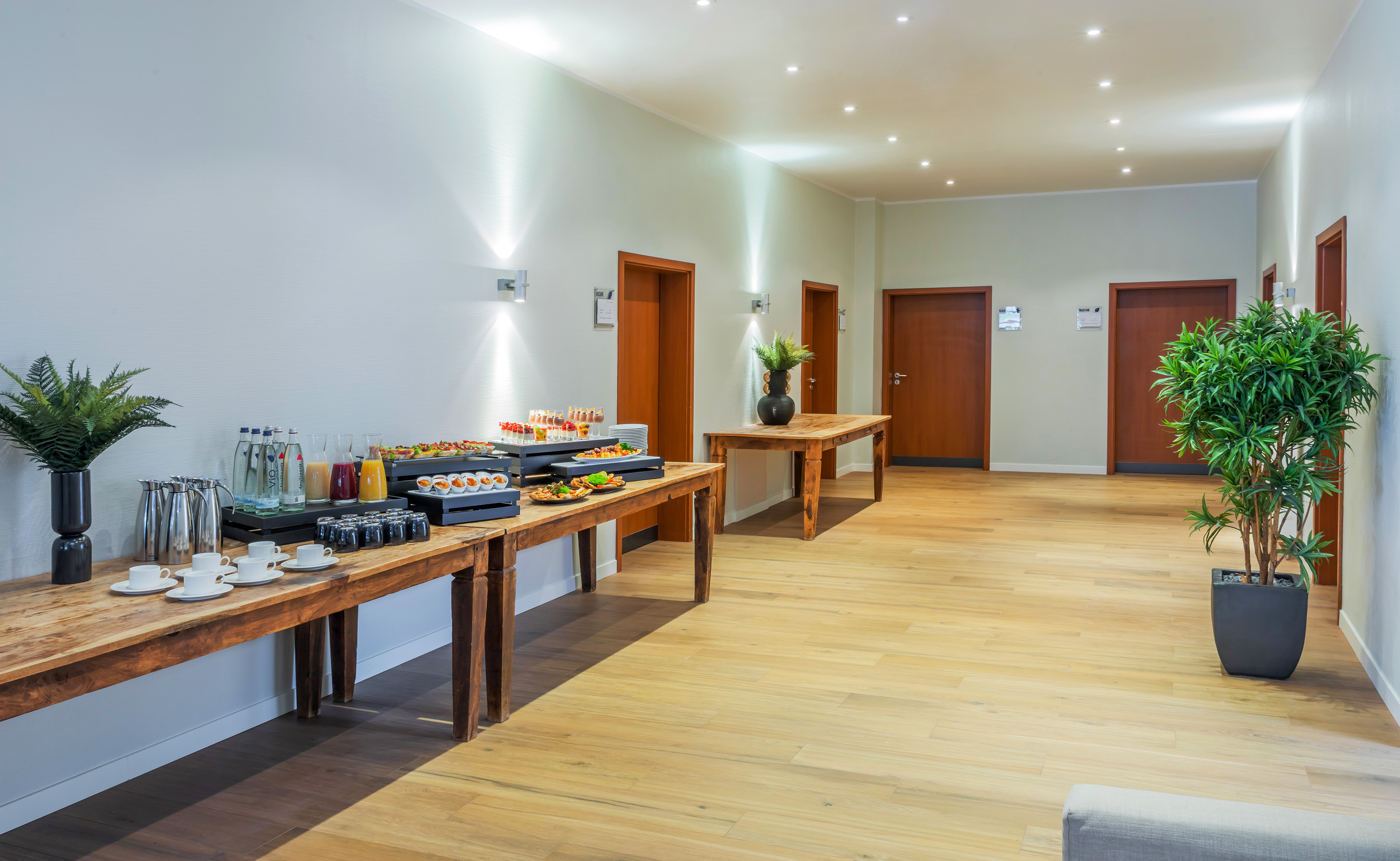 Bright foyer with event catering, snacks, drinks, and wooden buffet tables.
