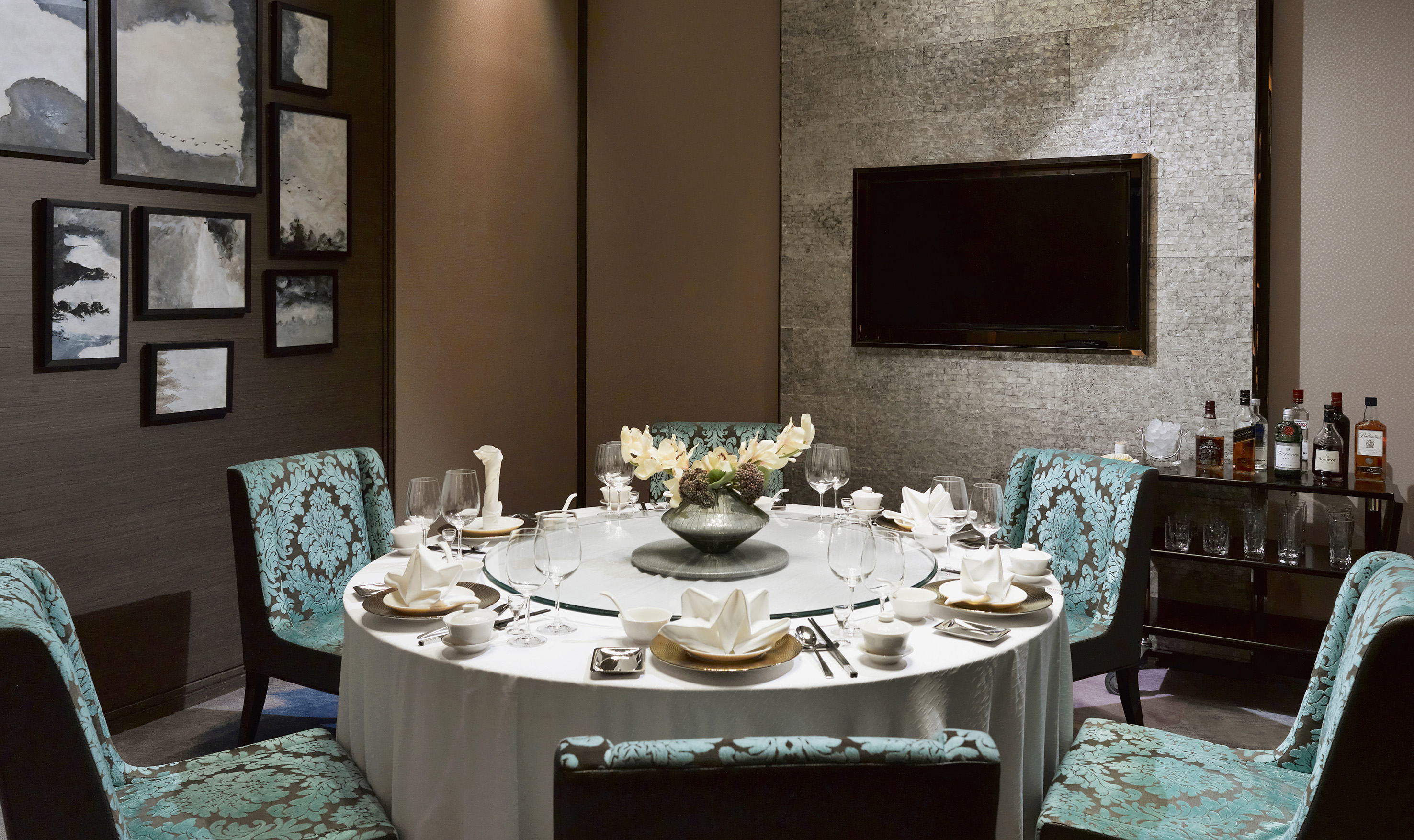 Elegant private dining room with set round table, patterned chairs, and wall art.