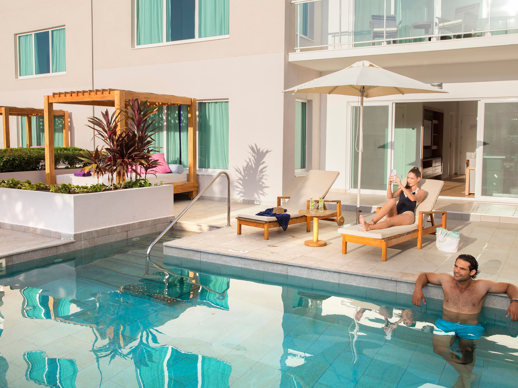 a man and woman sitting in chairs near a pool