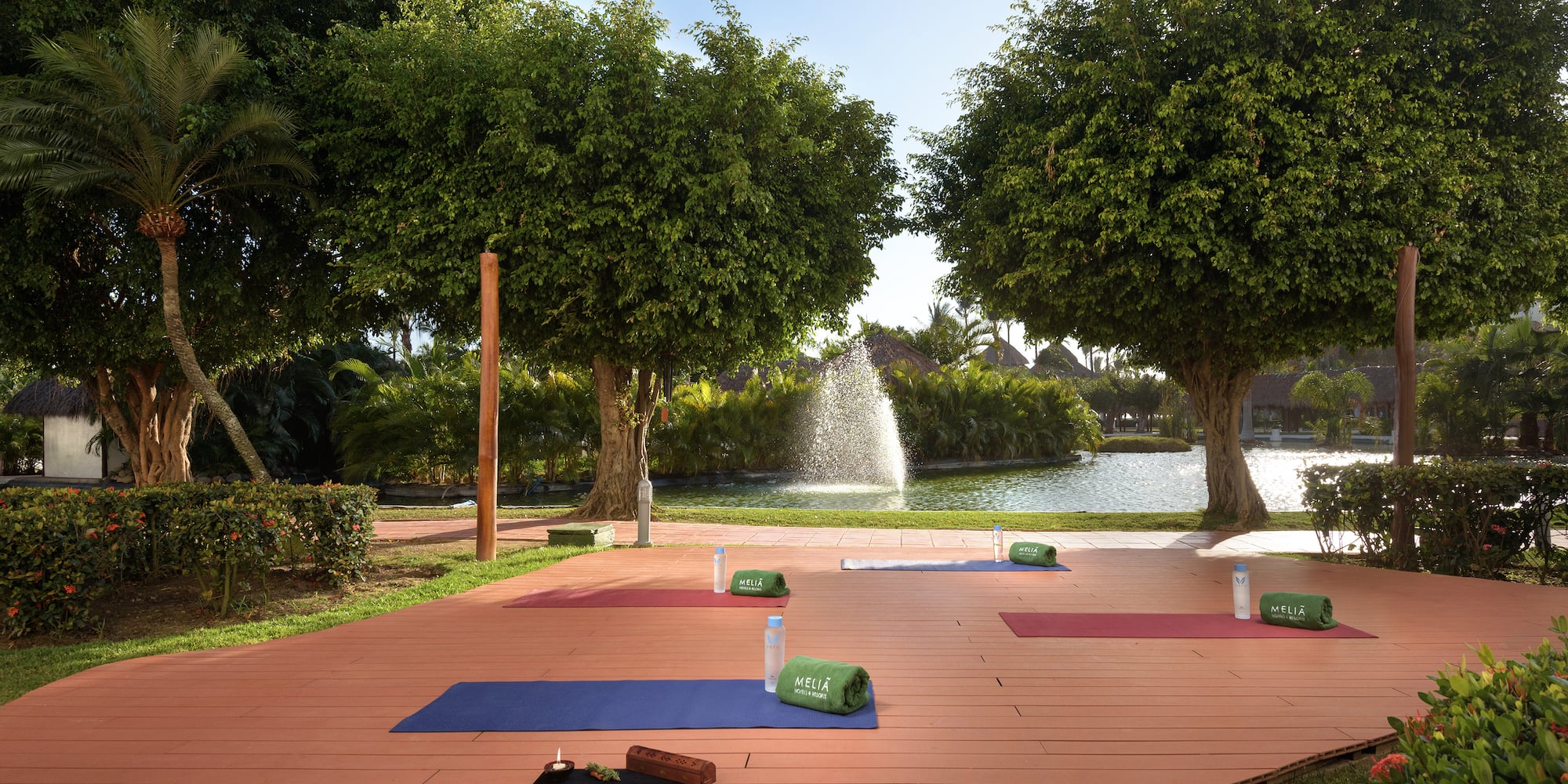 yoga mats on a wooden deck with trees and a fountain in the background