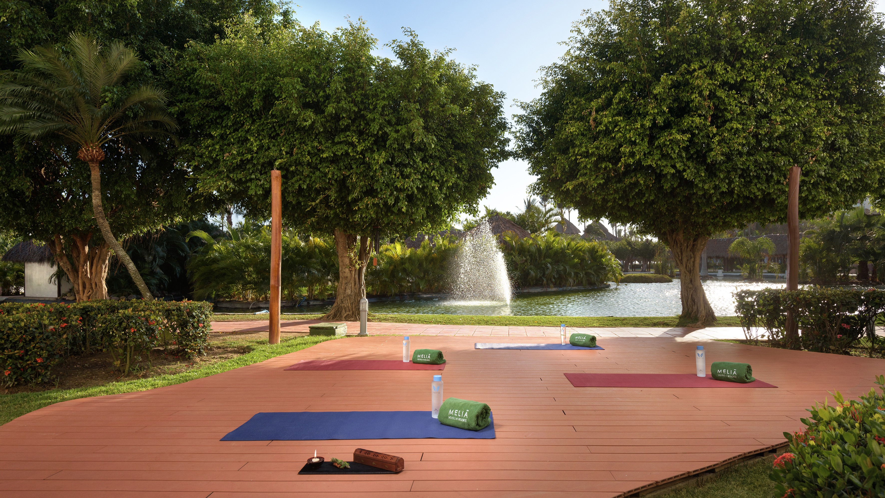 yoga mats on a wooden deck with trees and a fountain in the background
