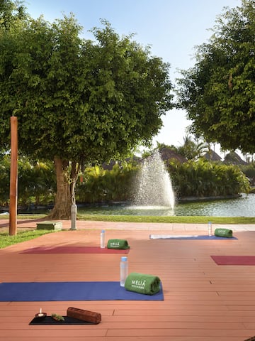 yoga mats on a wooden deck with trees and a fountain in the background