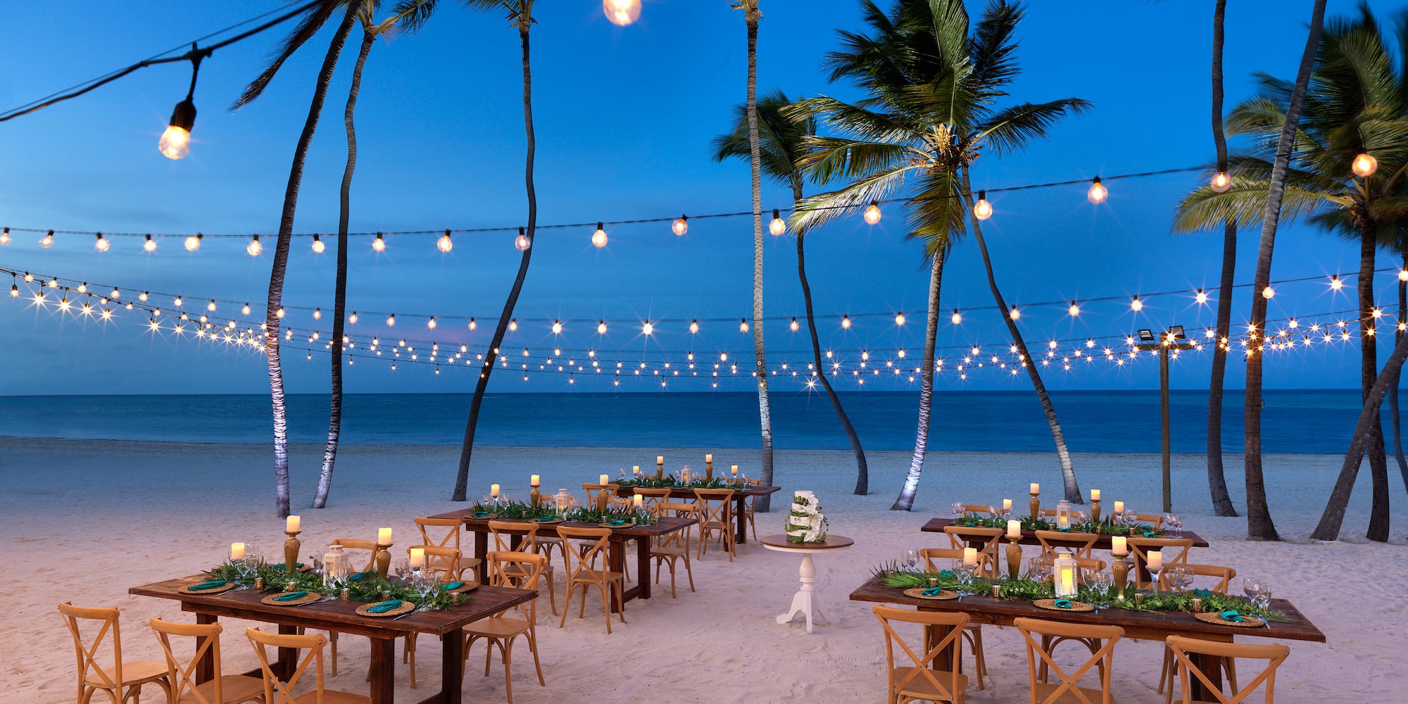 a beach with tables and chairs and palm trees