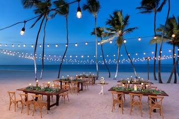 a beach with tables and chairs and palm trees