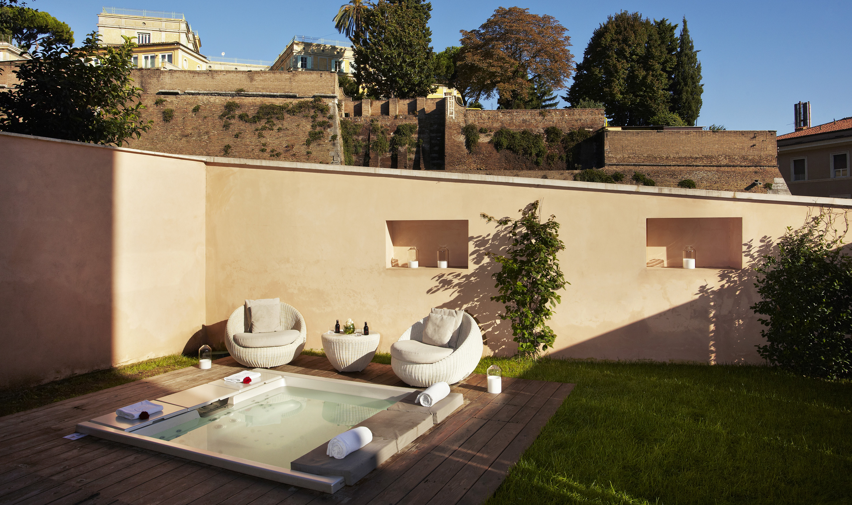 Outdoor jacuzzi, private patio, lounge chairs, and ancient brick wall.
