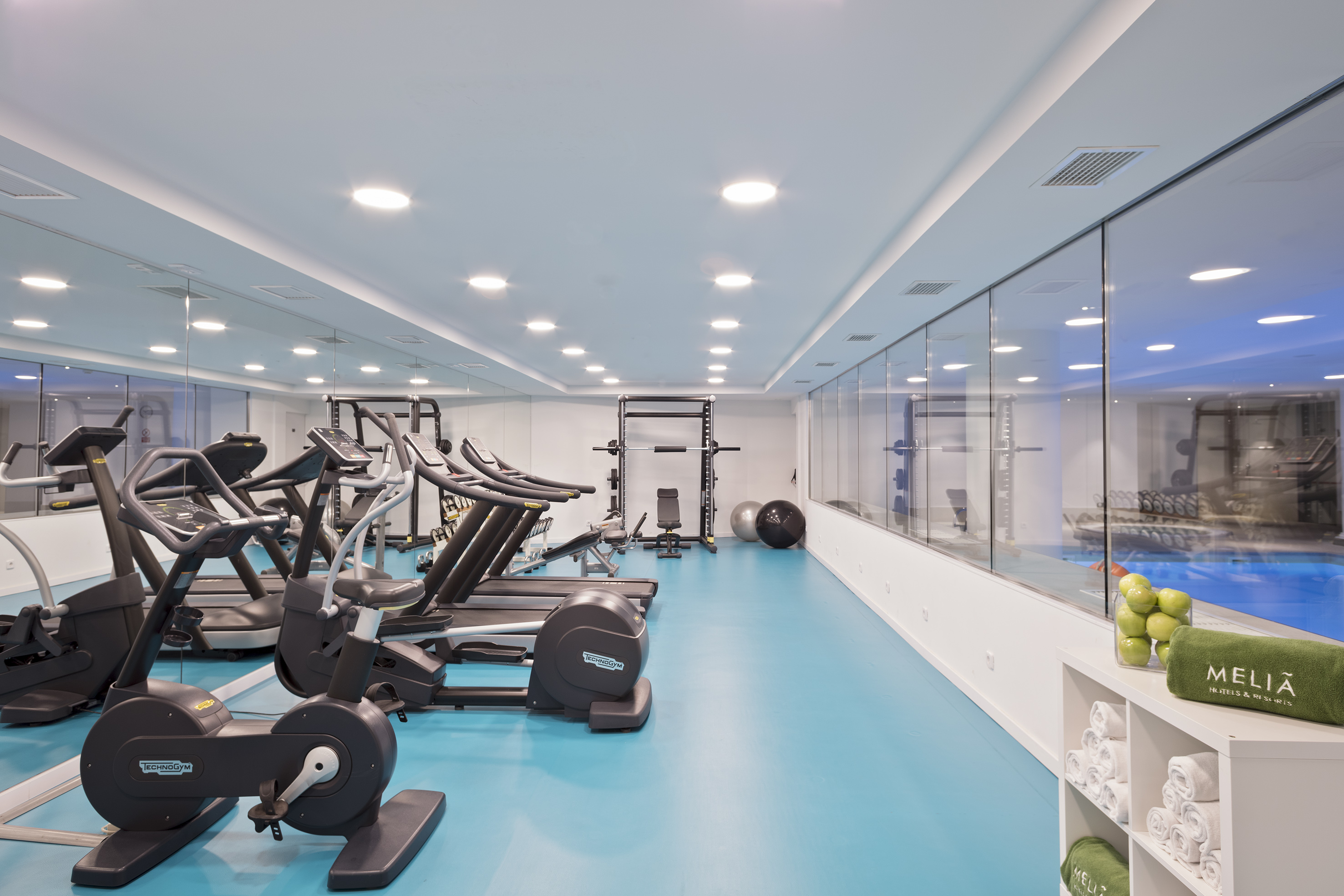 Meliá hotel gym with treadmills, weights, and indoor pool view.