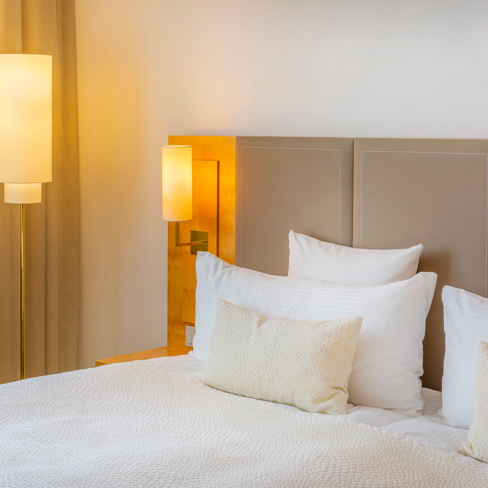 a bed with white pillows and a lamp next to it