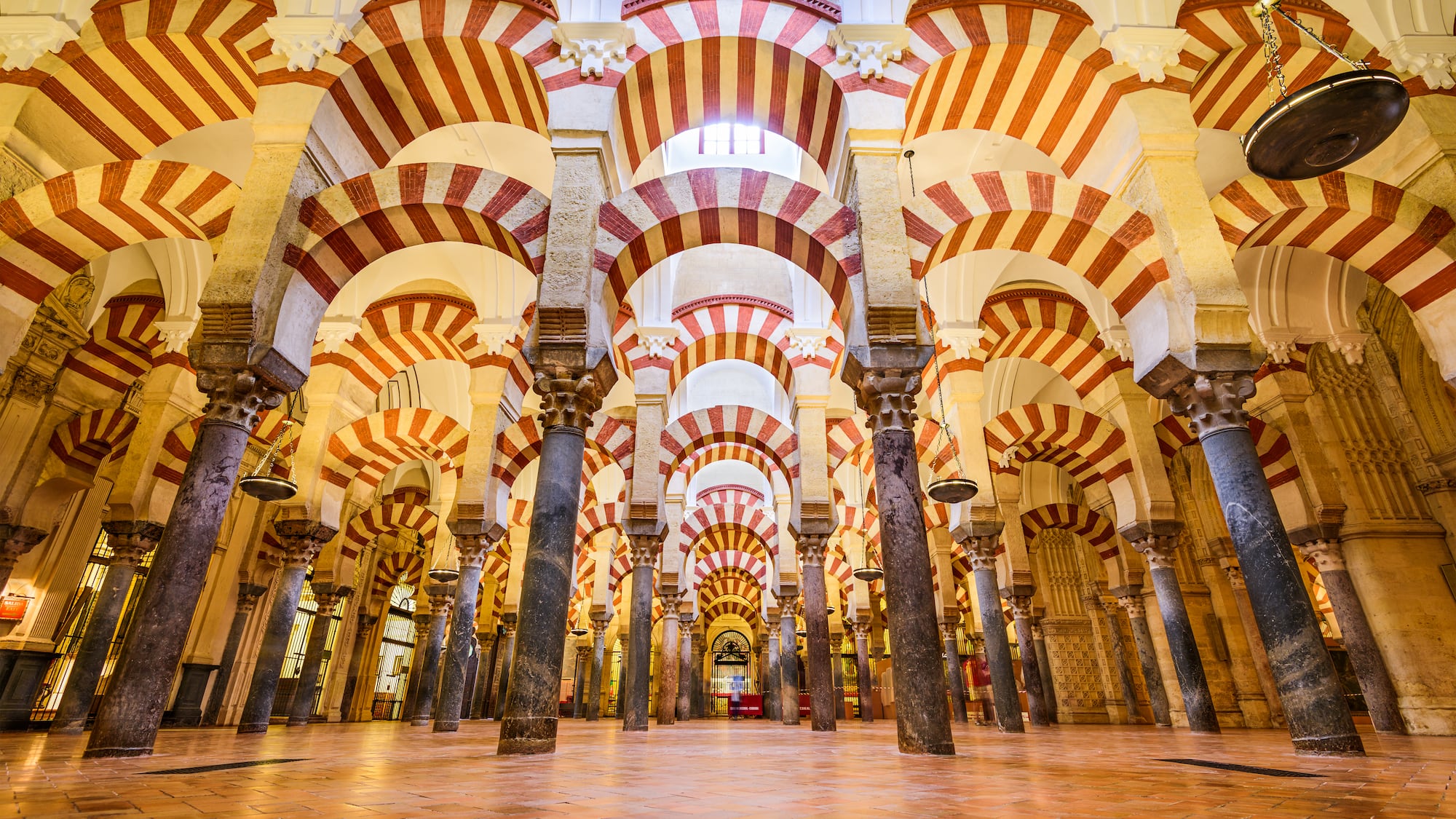 a large room with columns and arches with Mosque–Cathedral of Córdoba in the background