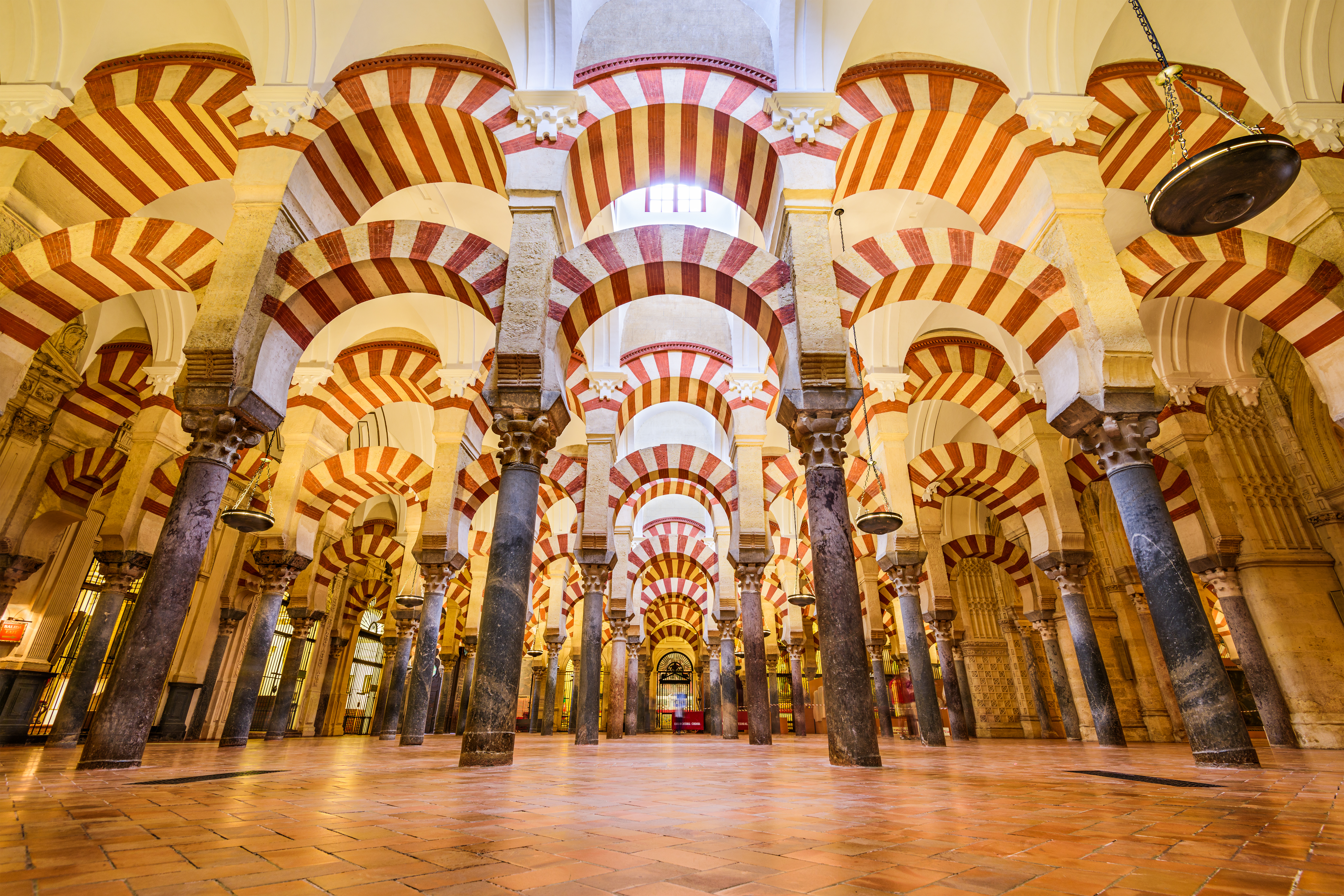 a large room with columns and arches with Mosque–Cathedral of Córdoba in the background