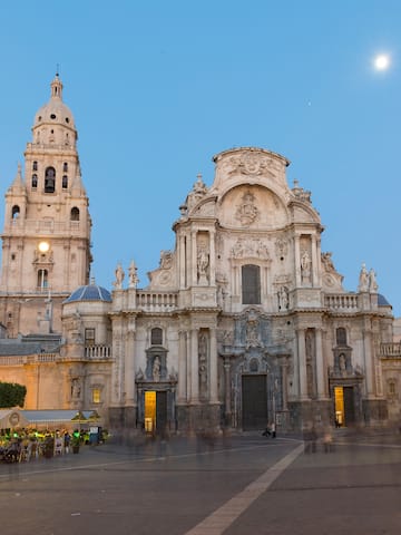 a large building with a clock tower with Cathedral of Murcia in the background