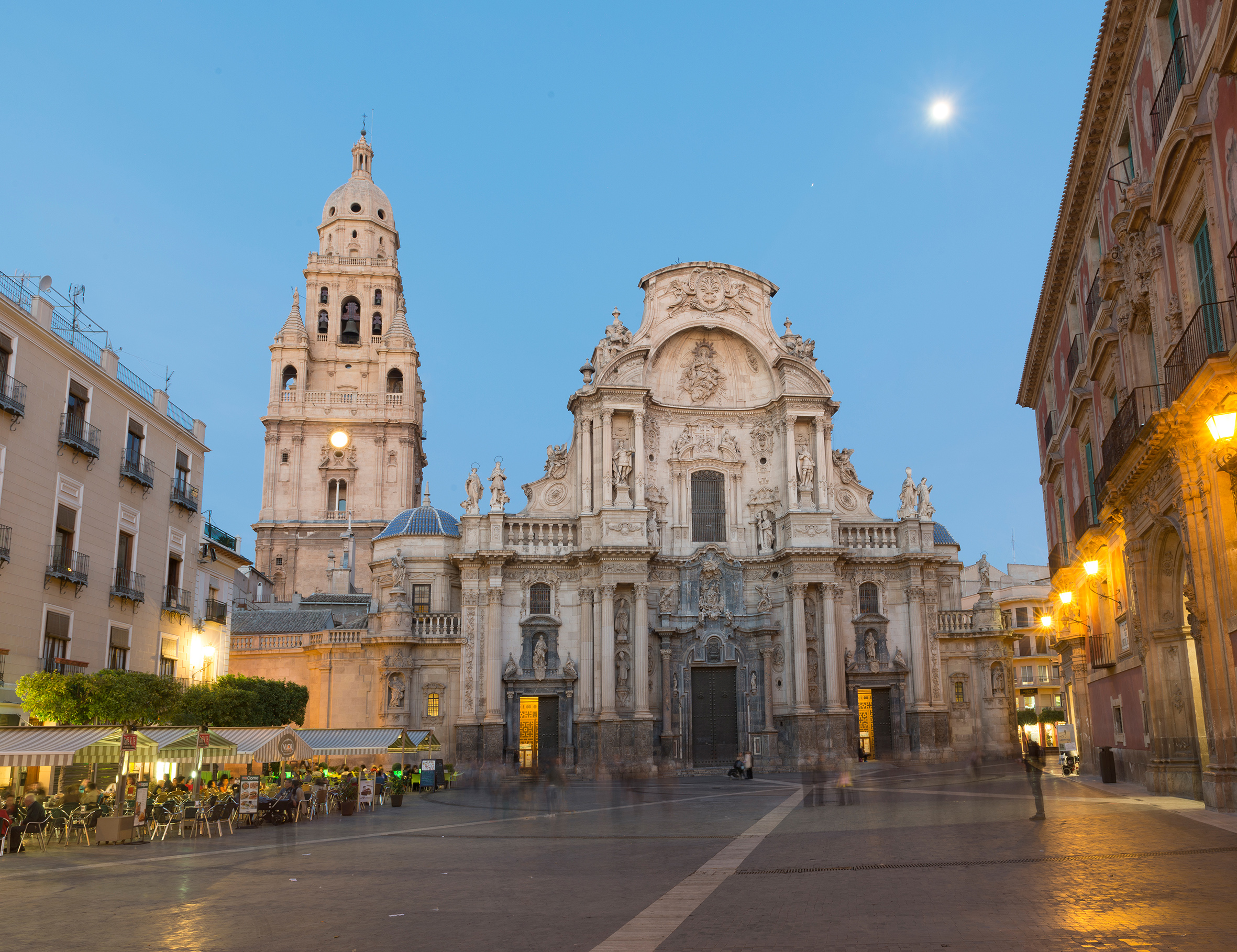 Murcia Cathedral and bell tower illuminated at twilight in Spanish plaza.