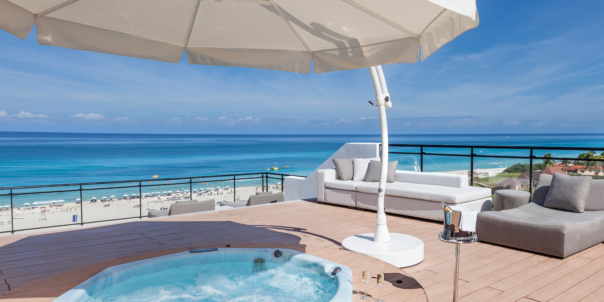 a hot tub on a deck with a beach and water in the background