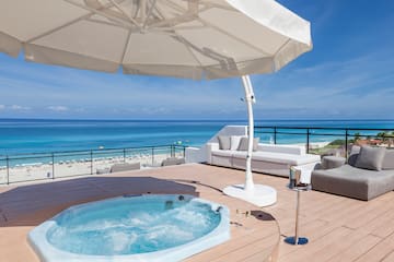 a hot tub on a deck with a beach and water in the background