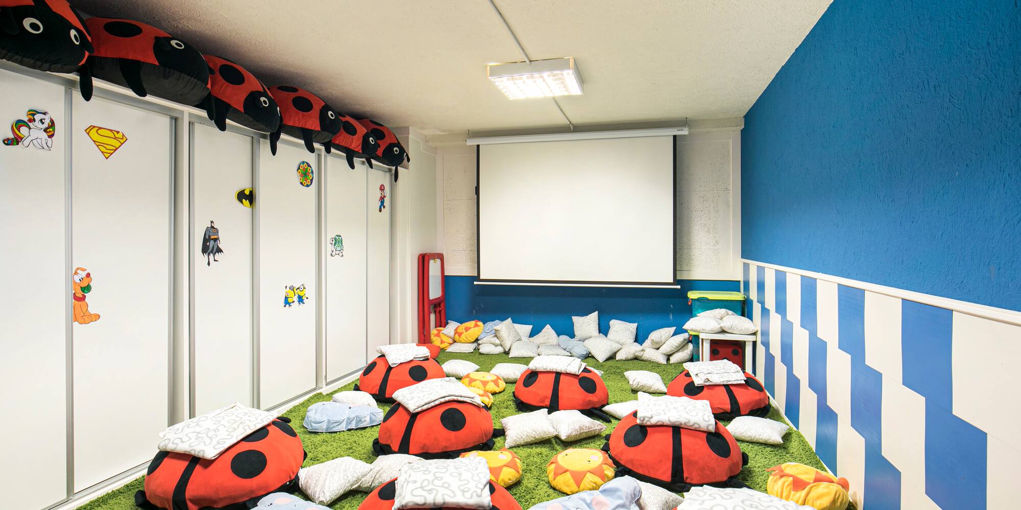 a room with ladybugs pillows and a projector screen