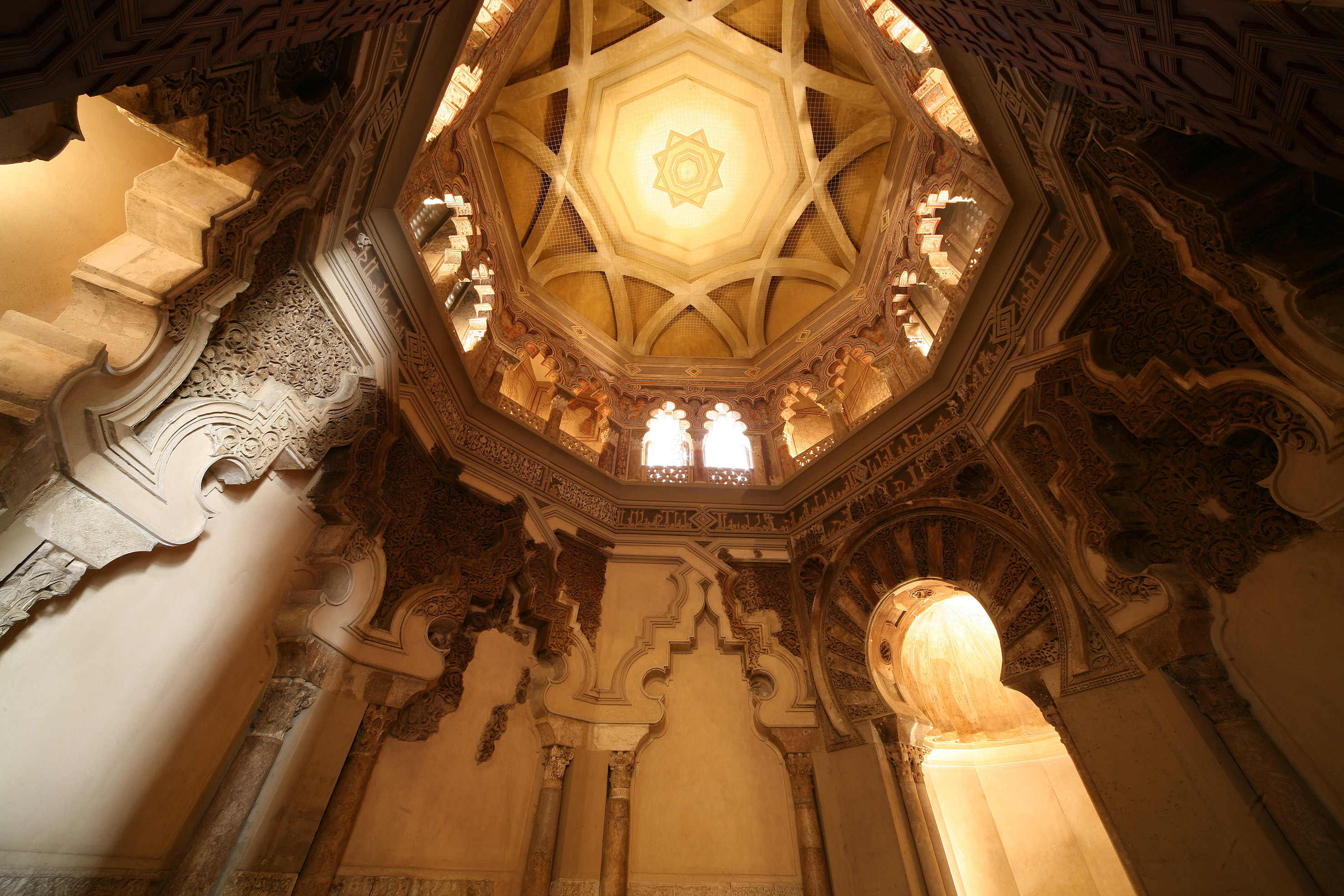 Grand interior view of Alcazar Seville's ornate dome with intricate carvings.