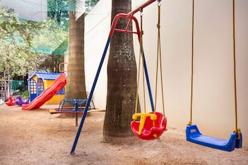 a playground with swings and a tree