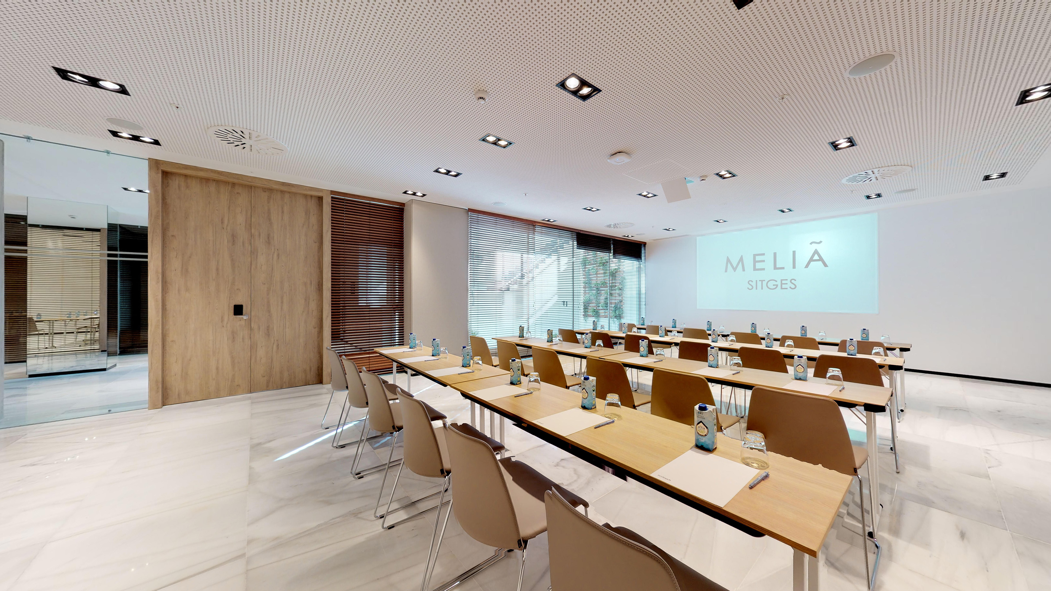 Modern conference room at Meliã Sitges with classroom setup and projector screen.