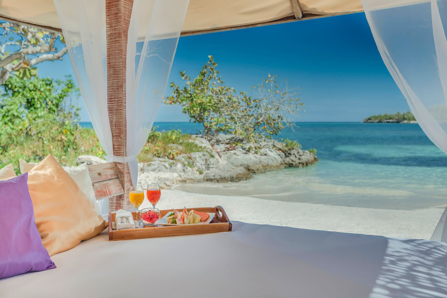 a tray of food on a bed with a beach view