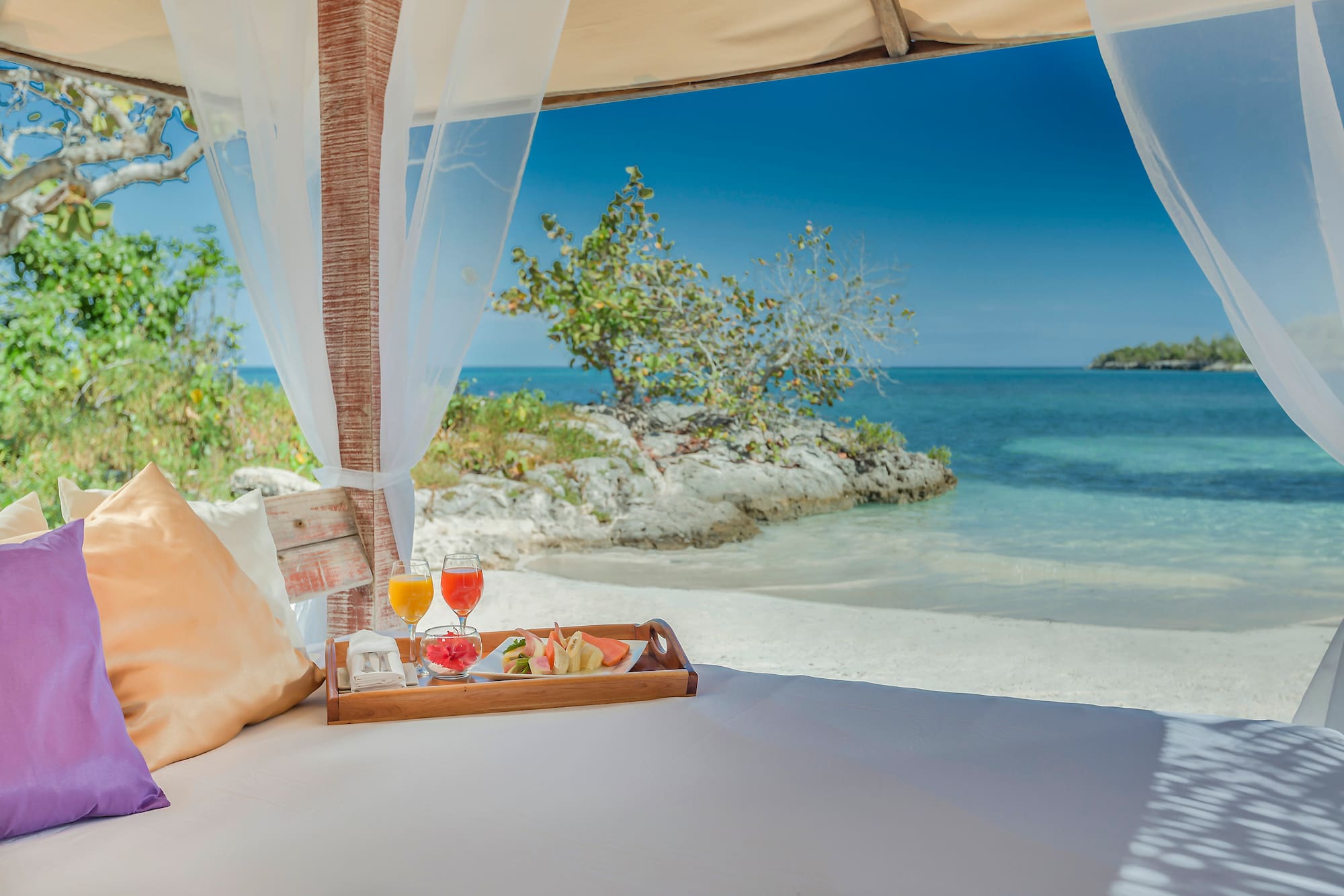 a tray of food on a bed with a beach view