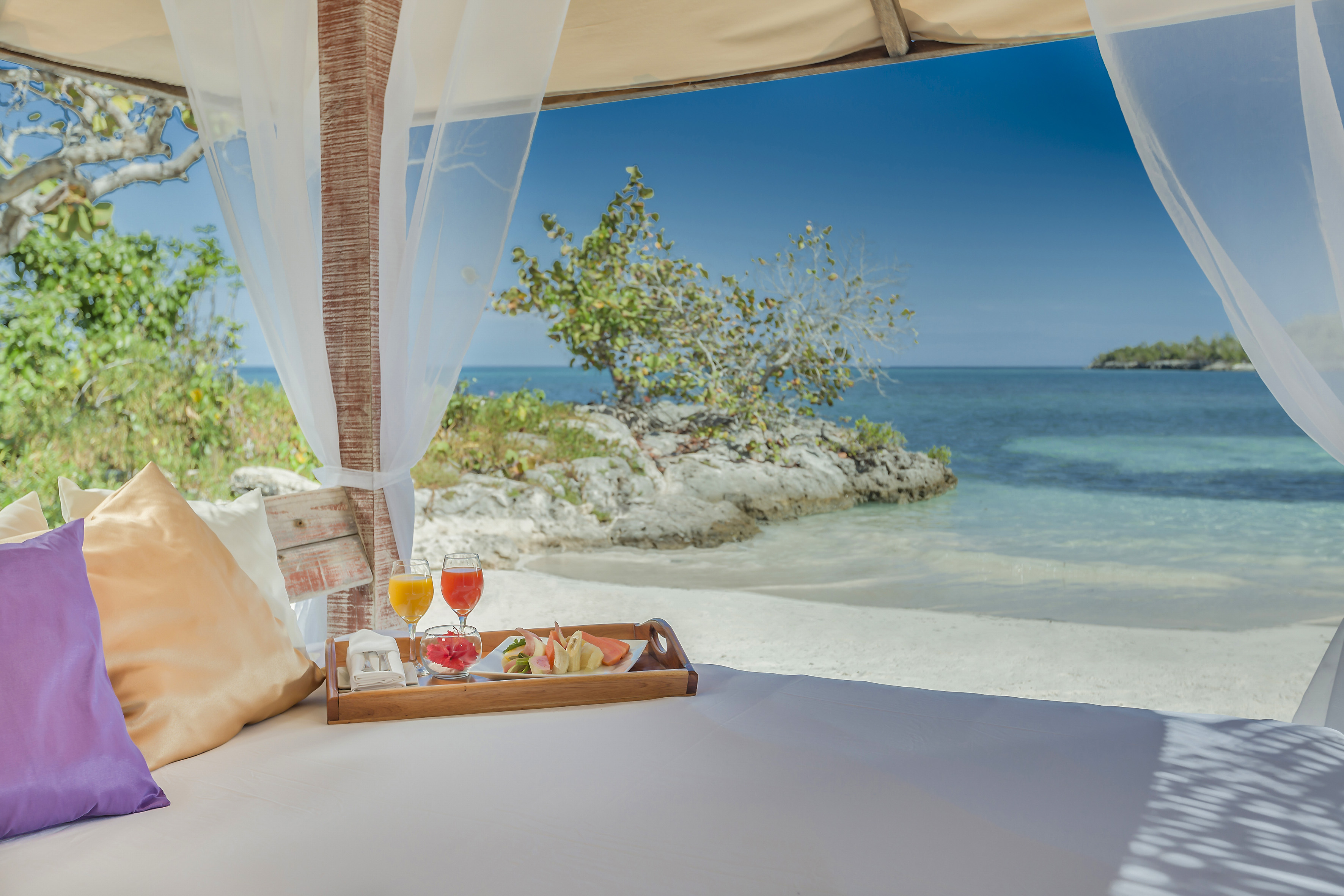 a tray of food on a bed with a beach view