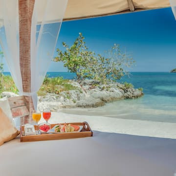 a tray of food on a bed with a beach view