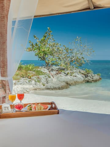a tray of food on a bed with a beach view