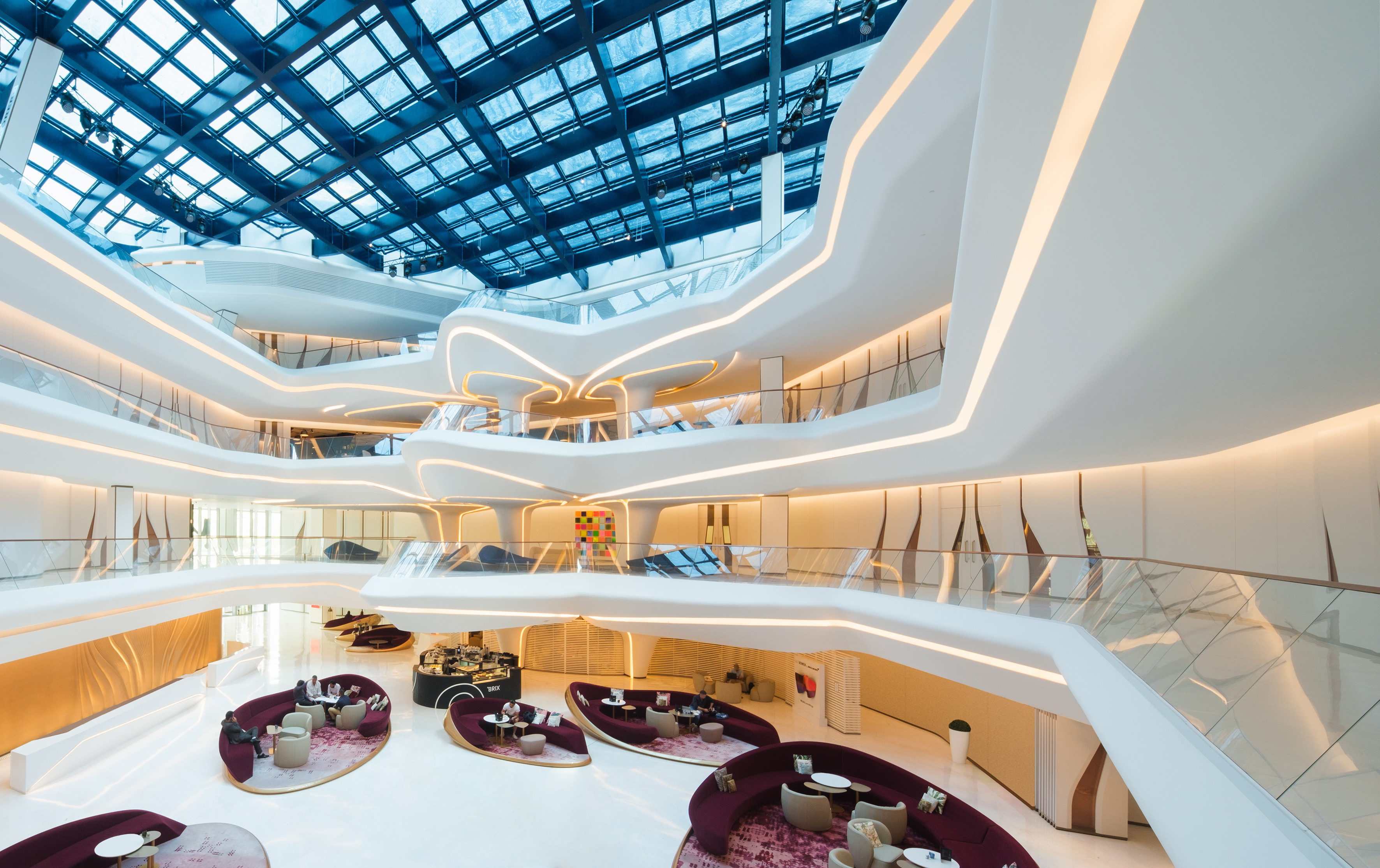 Curved white modern atrium with glass skylight and inviting lounge areas.