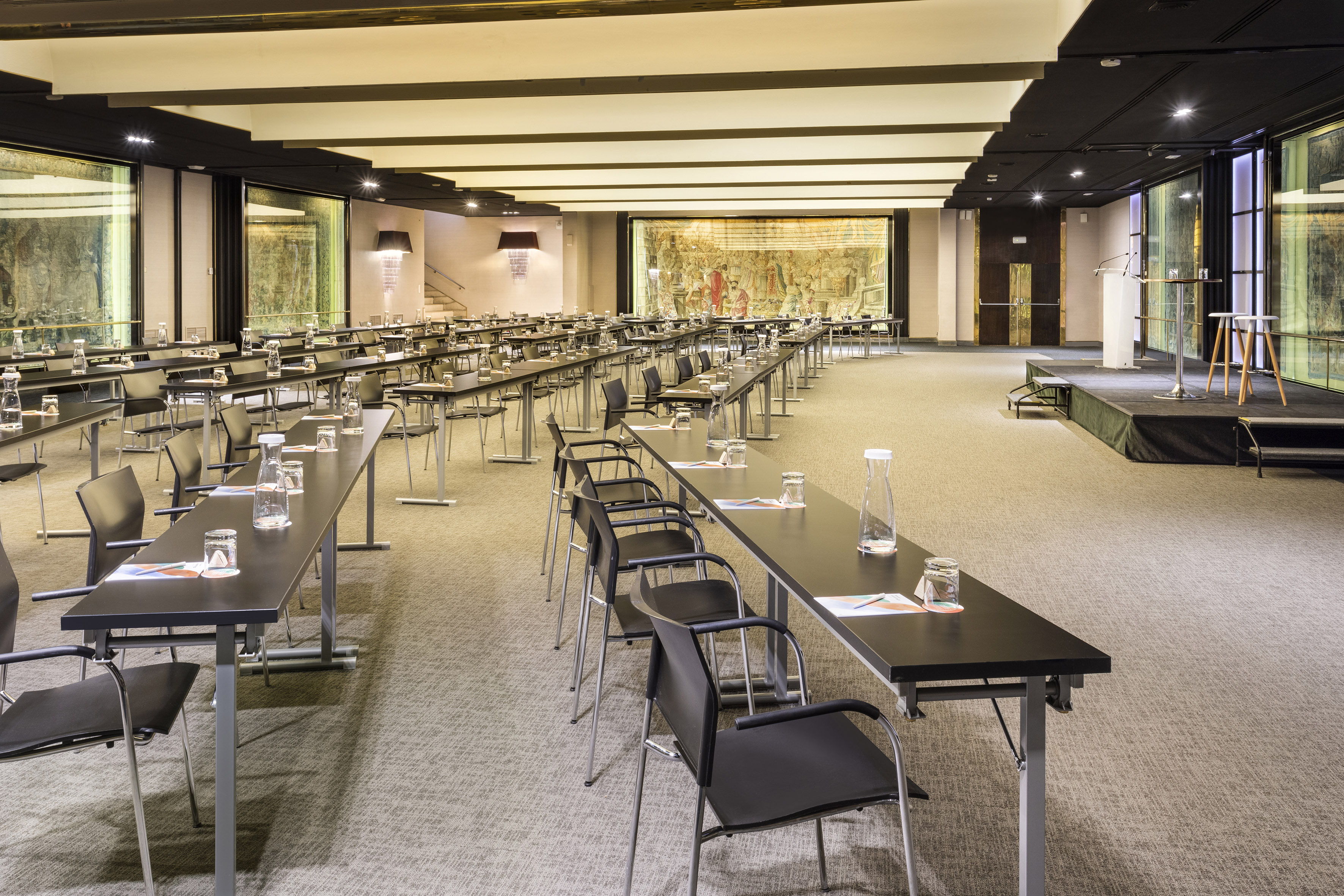 Large conference room set for a seminar with tables, chairs, and a stage.