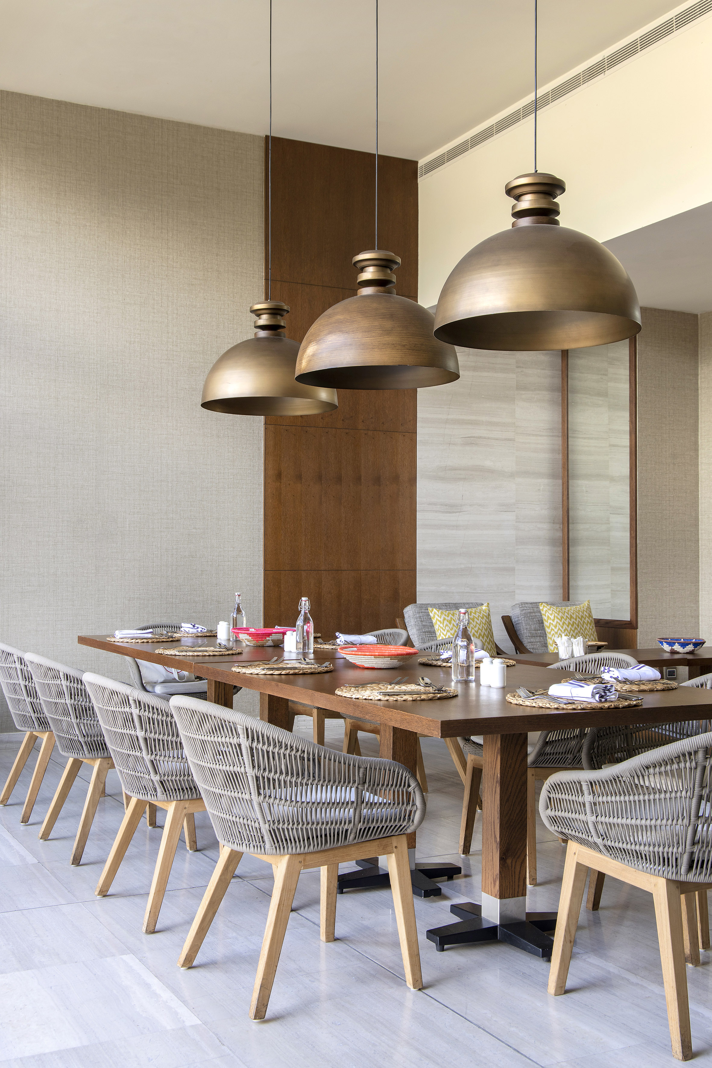 Dining room with wood table, woven chairs, and brass dome pendant lights.