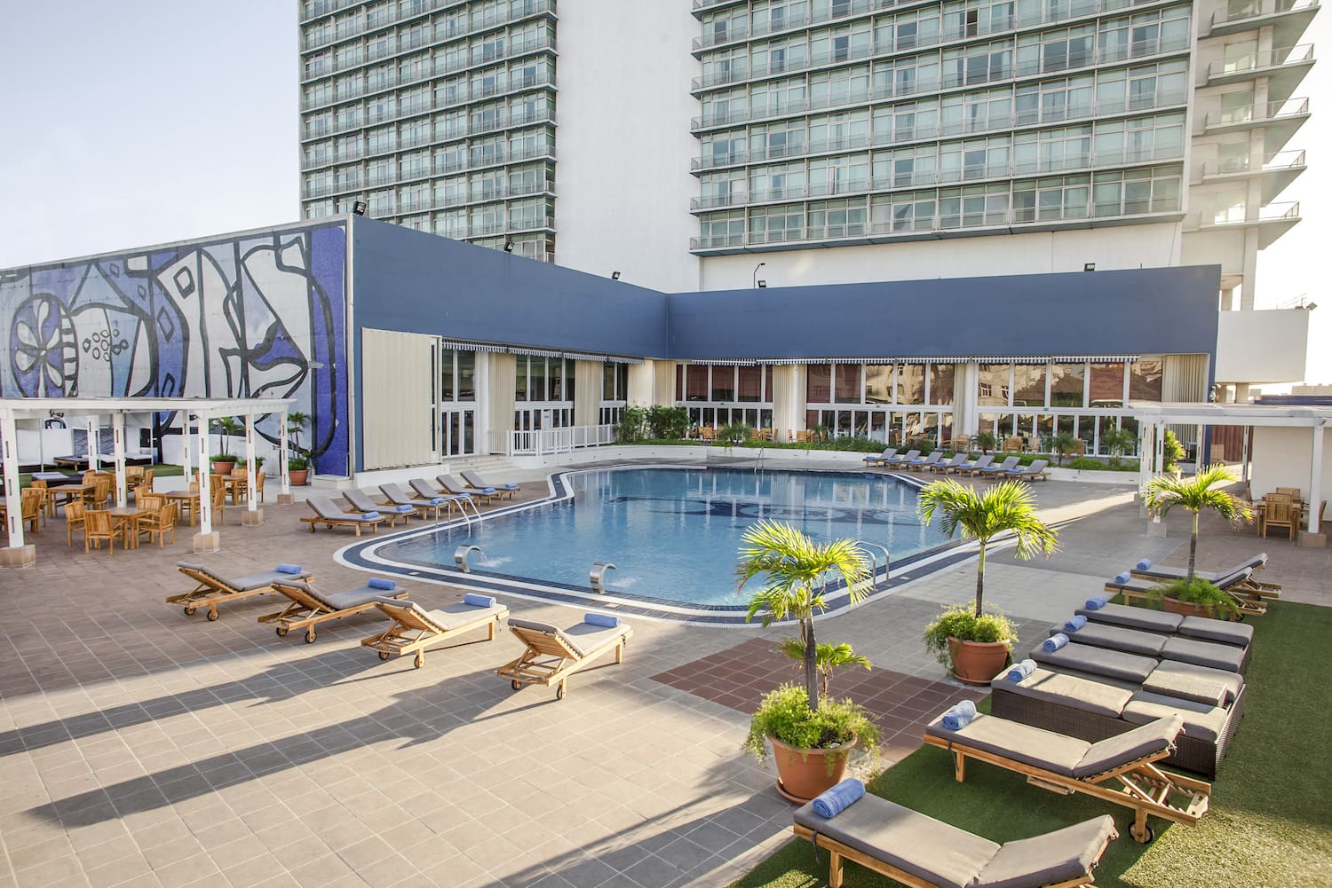 a pool with lounge chairs and a building with windows