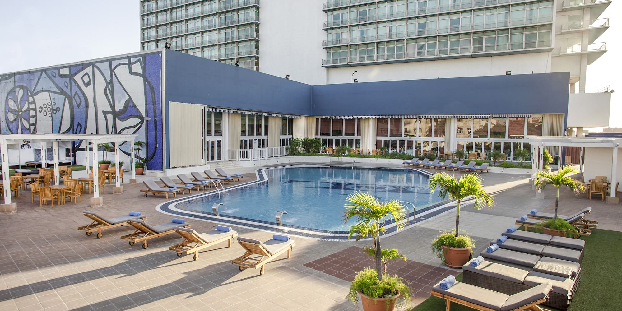a pool with lounge chairs and a building with windows