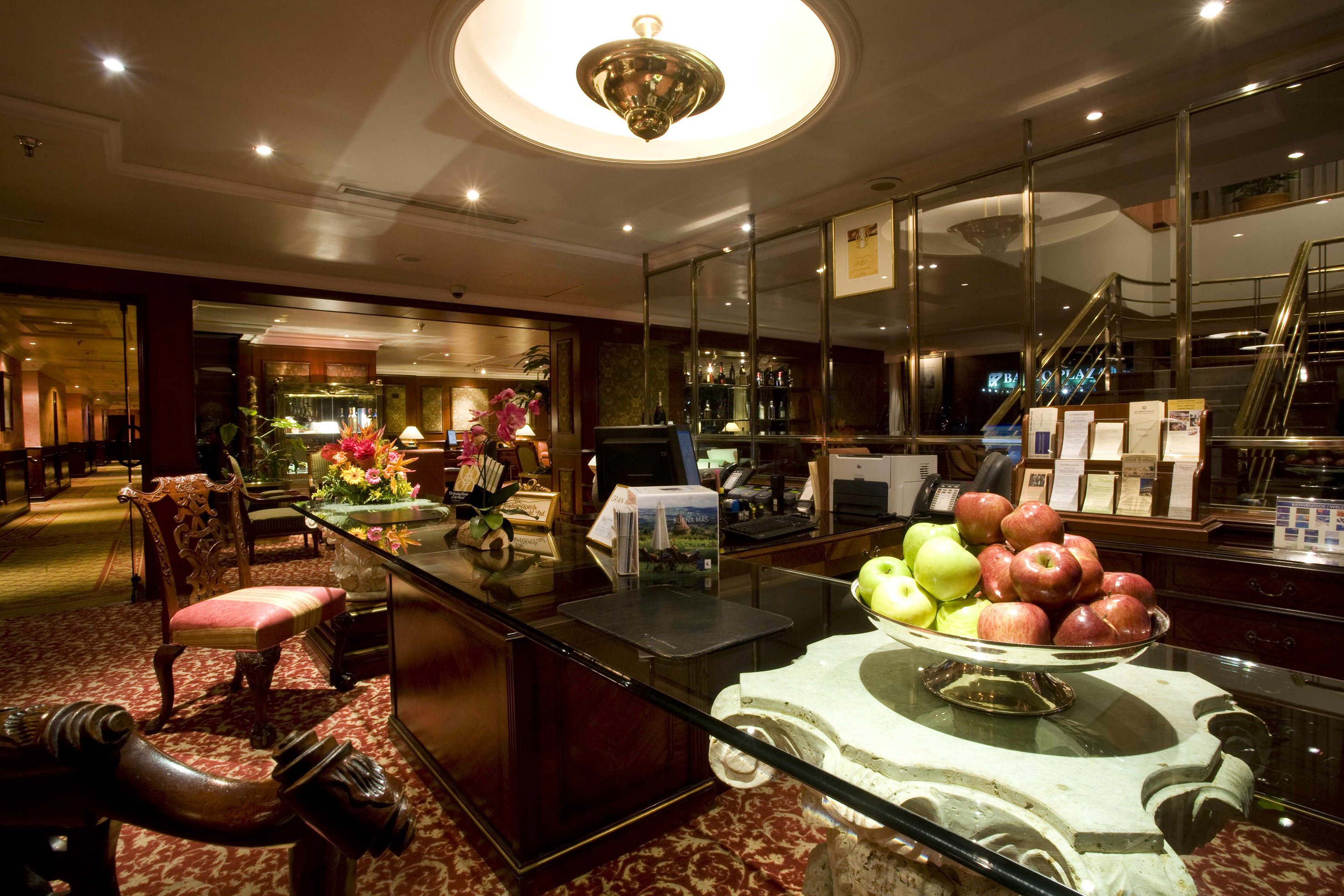 Hotel lobby reception desk with fresh apples, flowers, and luxurious interior.