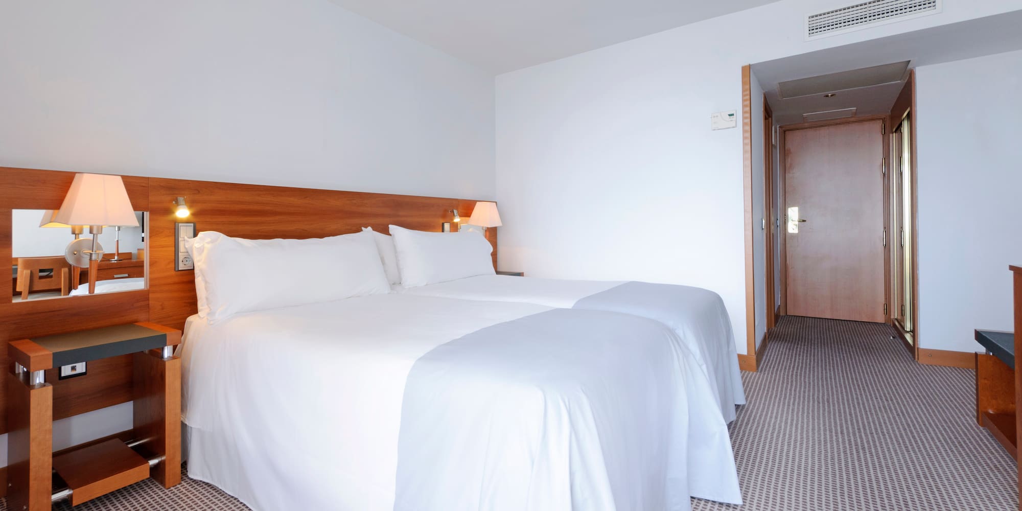a bed with white sheets and a wood headboard in a hotel room
